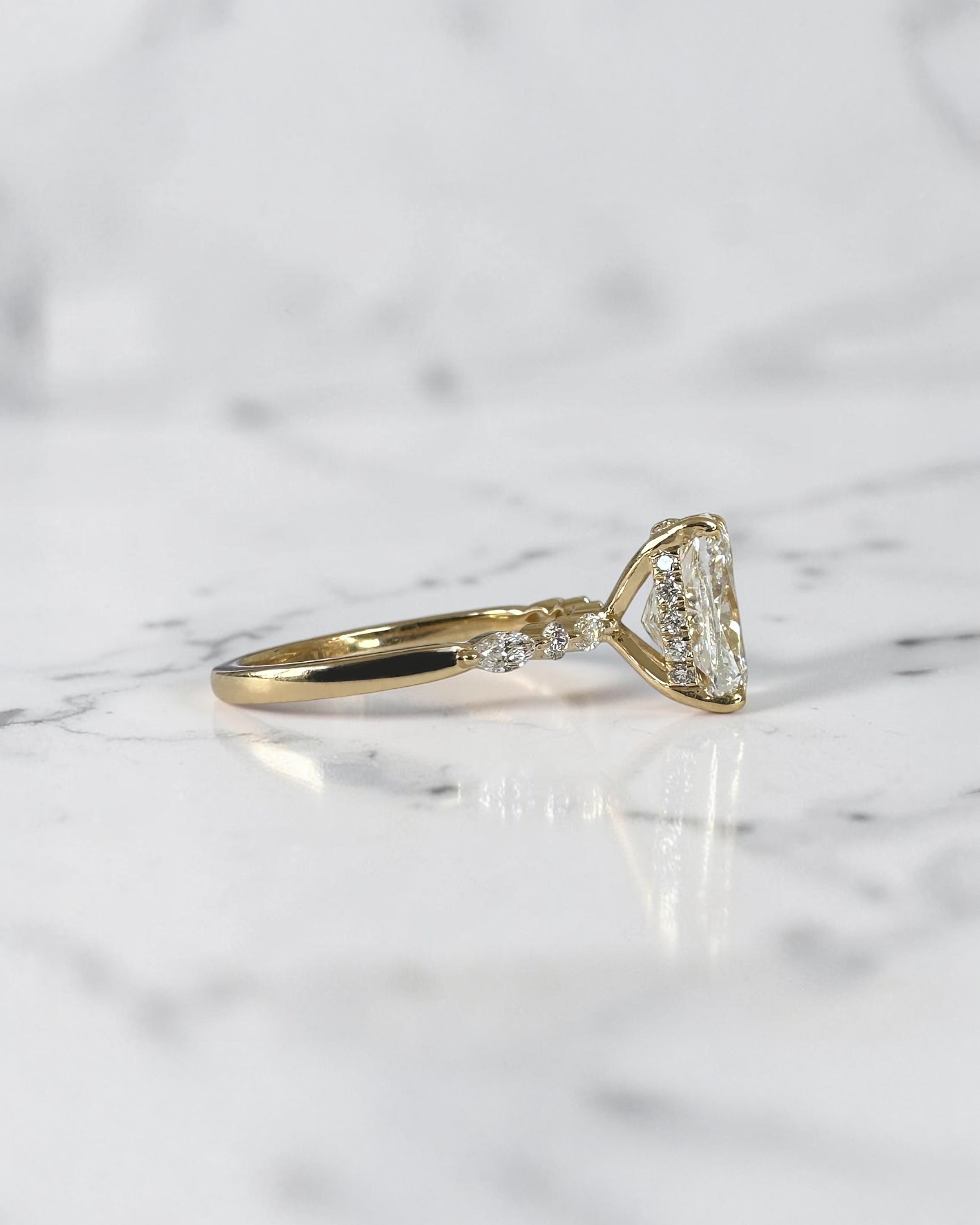 3ct elongated cushion cut lab grown diamond engagement ring featuring a hidden halo, floating head setting and marquise diamond band in 18kt yellow gold.
