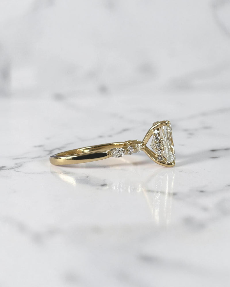 3ct elongated cushion cut lab grown diamond engagement ring featuring a hidden halo, floating head setting and marquise diamond band in 18kt yellow gold.
