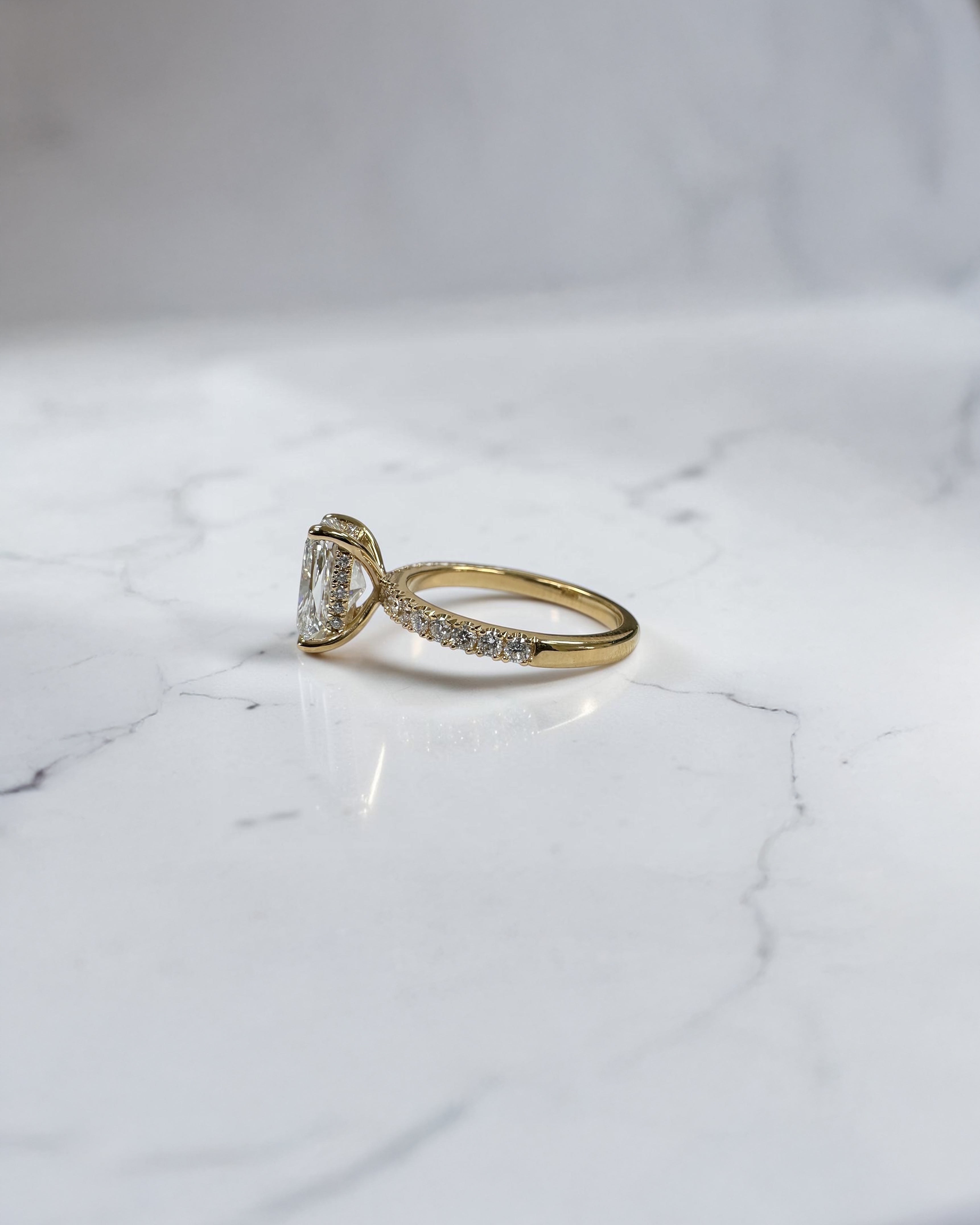 3ct elongated cushion cut diamond ring detail showing hidden halo and diamond bridge in yellow gold handcrafted in London UK