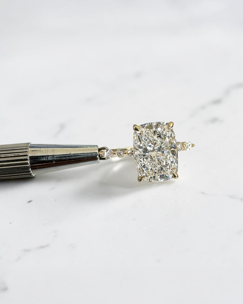 3ct elongated cushion cut lab grown diamond engagement ring with hidden halo, floating head setting and marquise and round diamond band in yellow gold, handmade in London.

