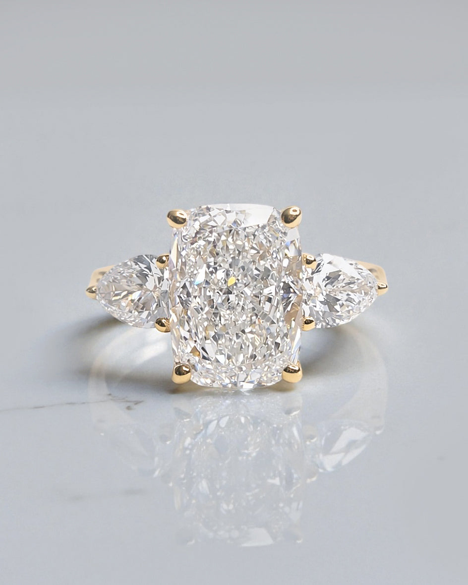 3ct cushion cut lab grown diamond trilogy engagement ring with pear side stones in yellow gold
