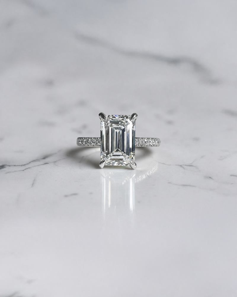 3ct emerald cut diamond engagement ring with open prongs and pavé diamond band in white gold, total 3.38ct