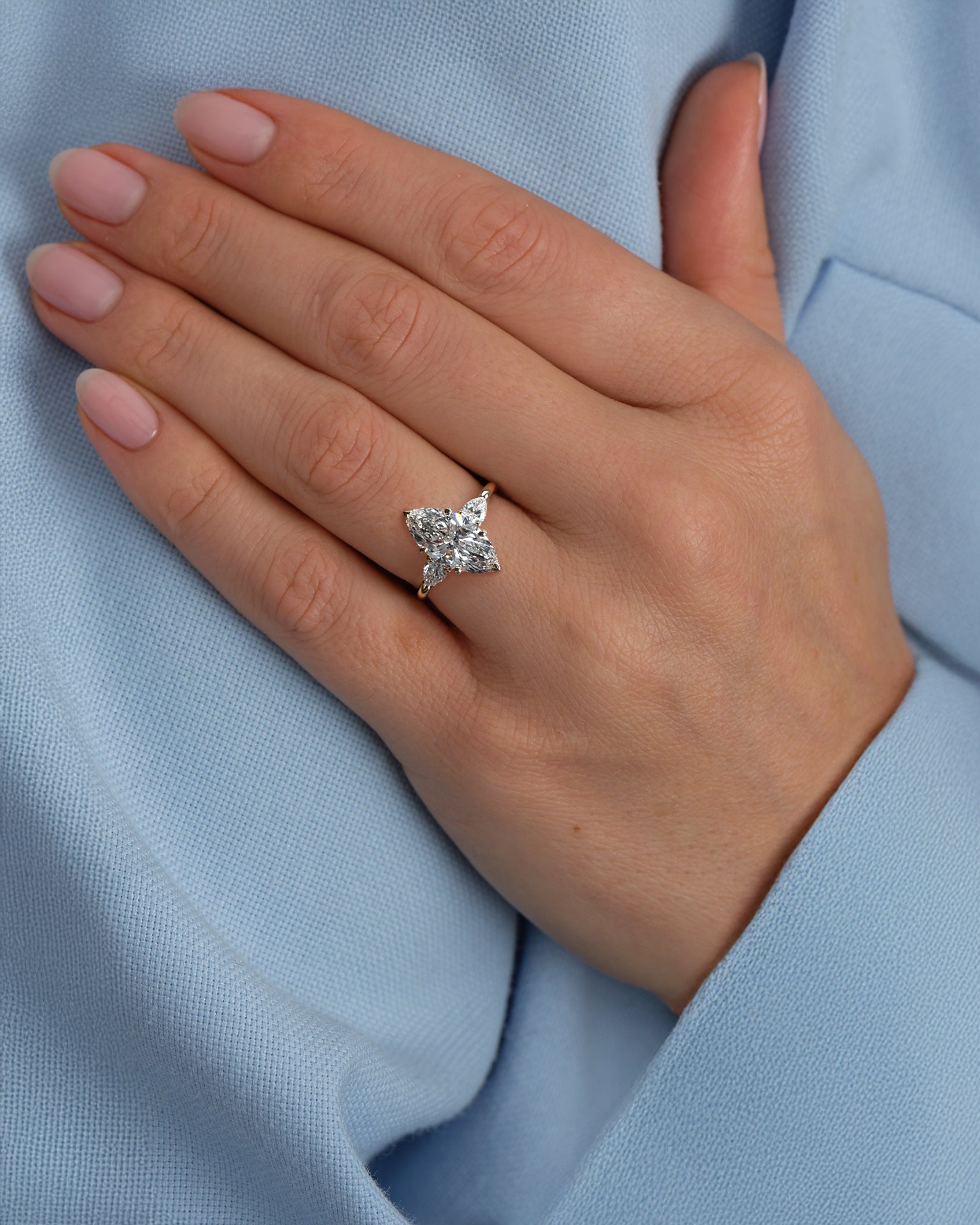 3ct marquise cut diamond trilogy engagement ring with pear cut side stones worn on hand, designed by Layla Diamonds 18kt yellow gold