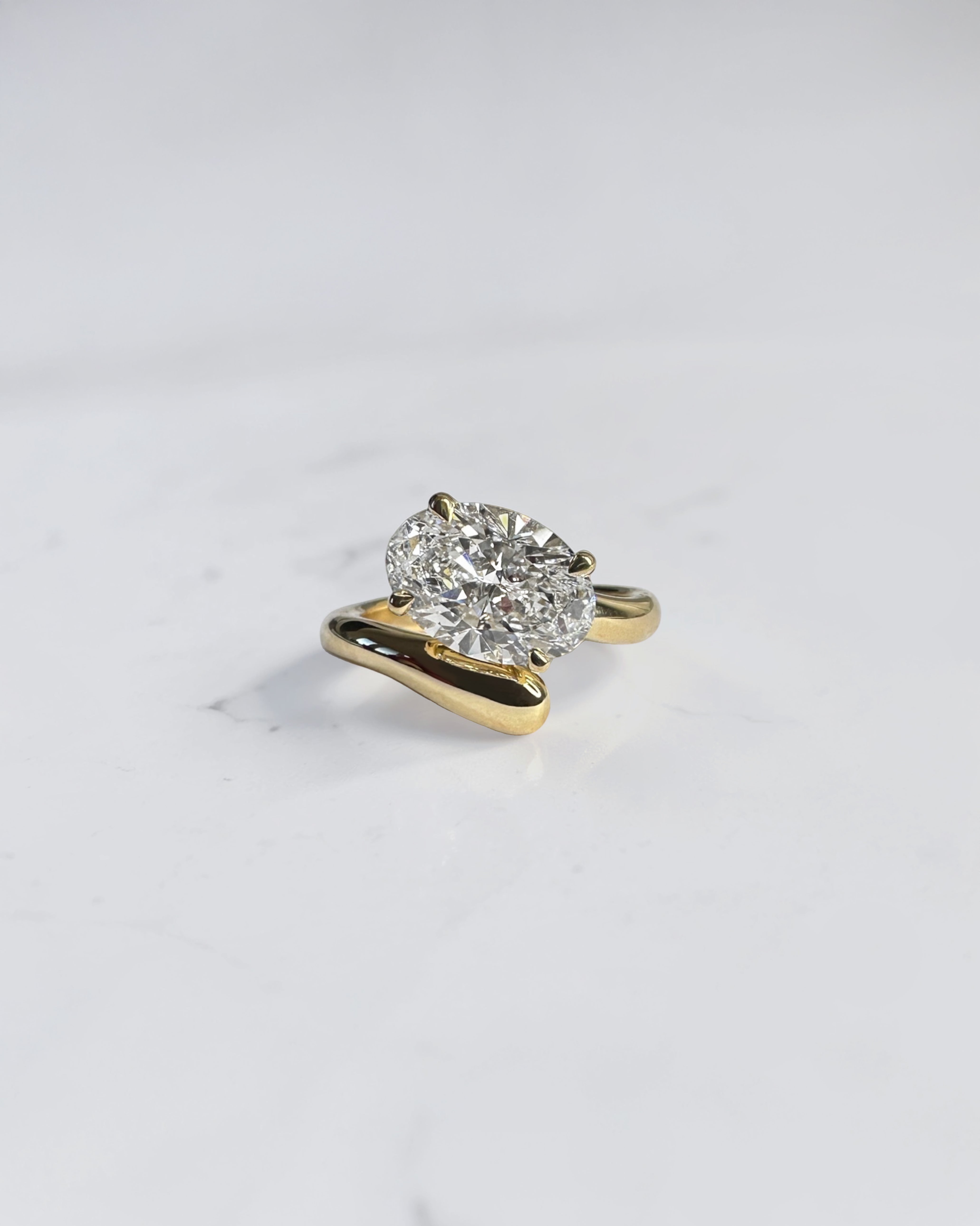 Oval cut diamond sculptural wrap engagement ring in 18kt yellow gold, open band bypass design, handcrafted in London