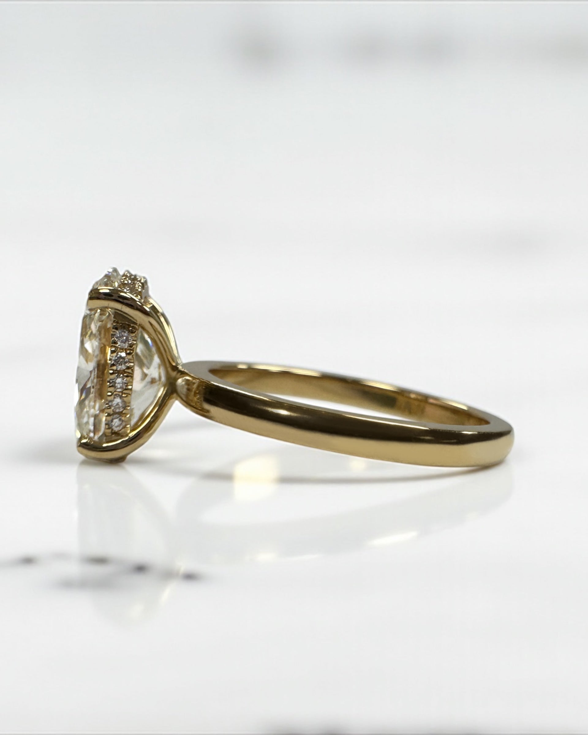 3ct oval cut lab grown diamond floating head engagement ring 18kt yellow gold with hidden halo on a plain soft court band