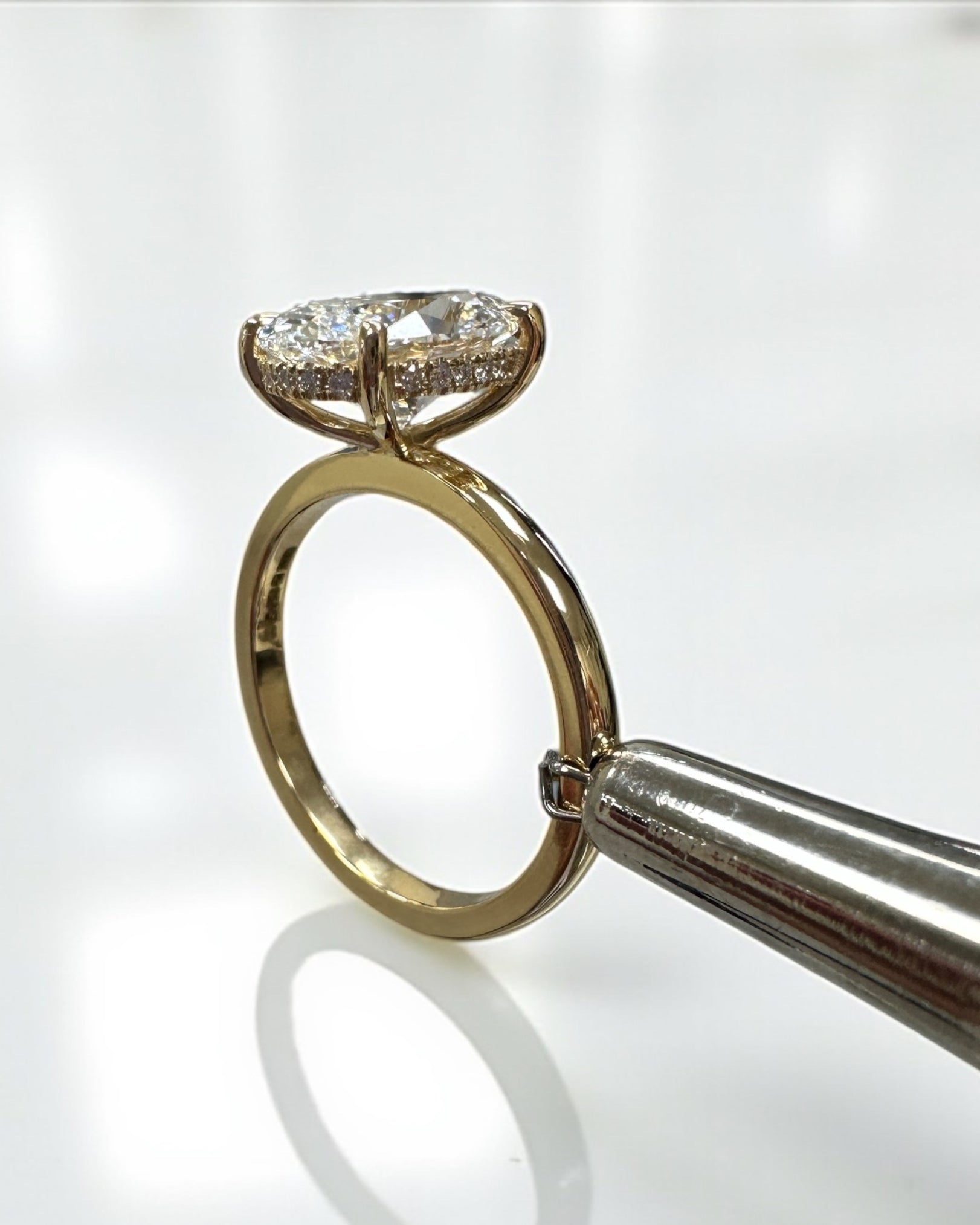 3ct oval cut lab grown diamond floating head engagement ring 18kt yellow gold with hidden halo on a plain soft court band