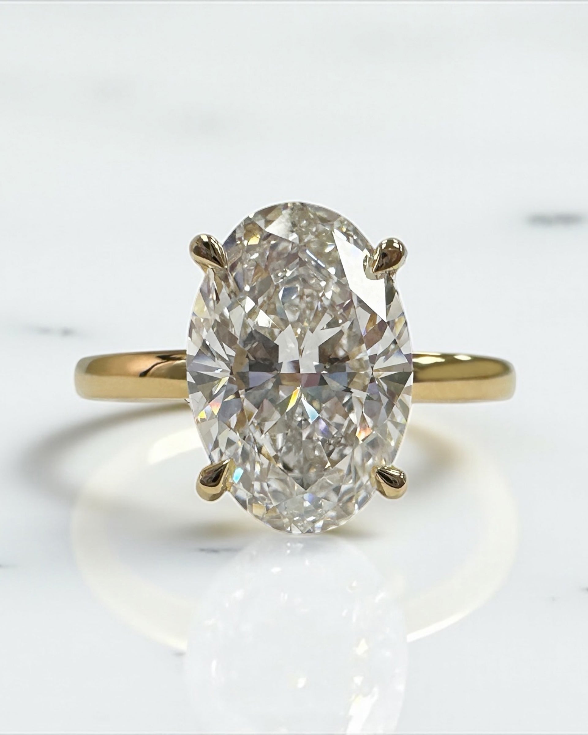 3ct oval cut lab grown diamond floating head engagement ring 18kt yellow gold with hidden halo on a plain soft court band
