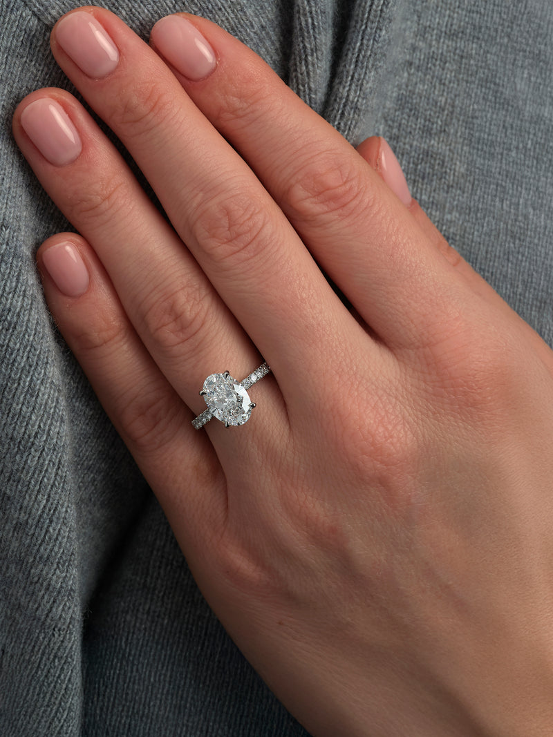 3ct oval cut lab grown diamond engagement ring on hand with floating head, hidden halo and diamond shoulders by Layla Diamonds.
