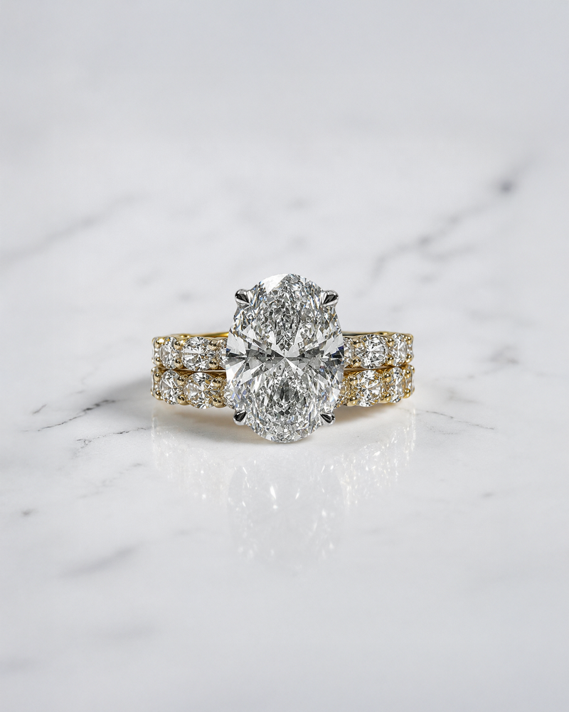 3ct oval cut lab grown diamond hidden halo engagement ring with east west oval diamond band in two tone platinum and 18kt yellow gold.