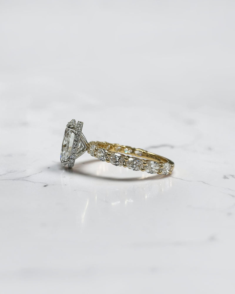 3ct oval cut lab grown diamond hidden halo engagement ring with east west oval diamond band in two tone platinum and 18kt yellow gold.