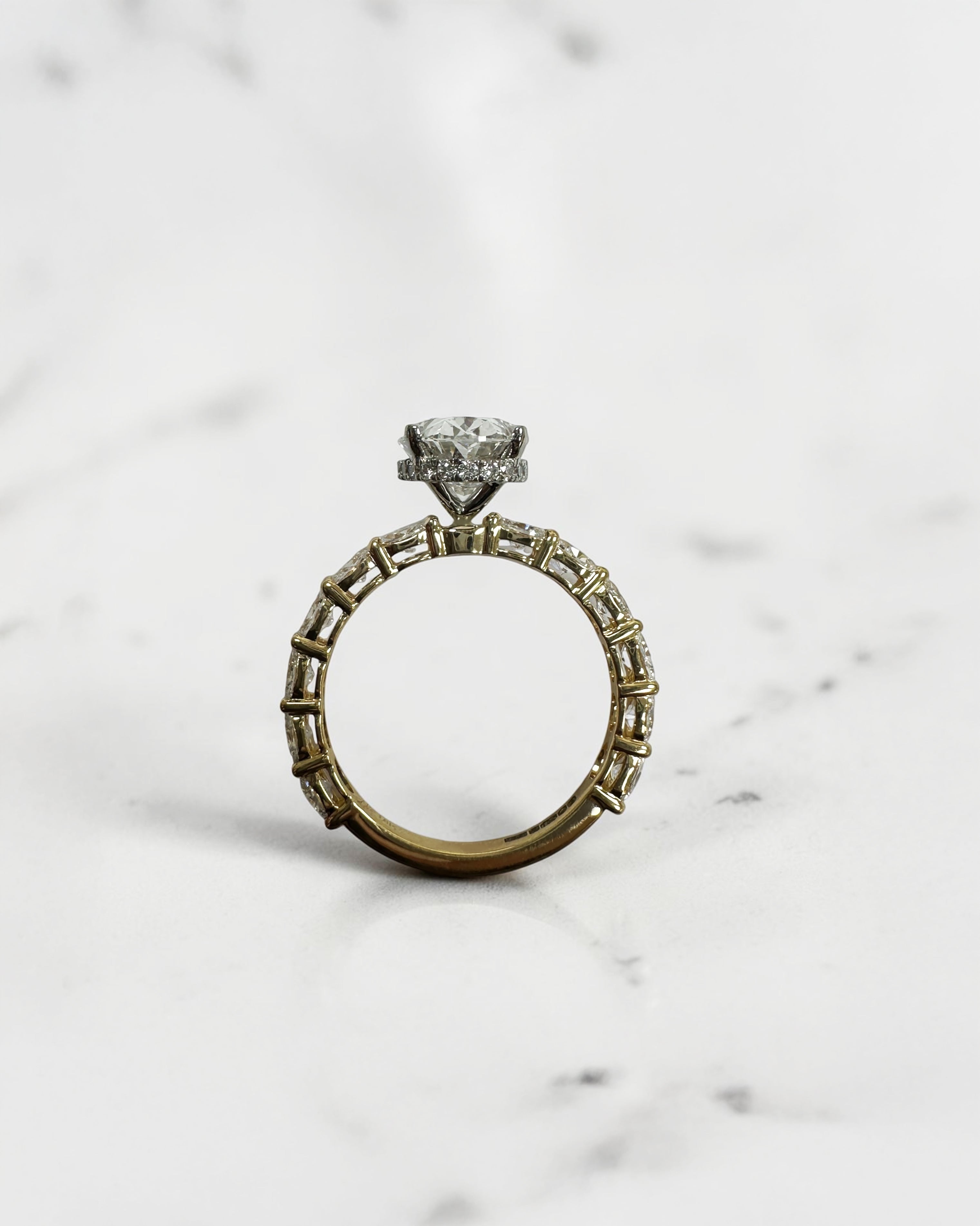 3ct oval cut lab grown diamond hidden halo engagement ring with east west oval diamond band in two tone platinum and 18kt yellow gold.
