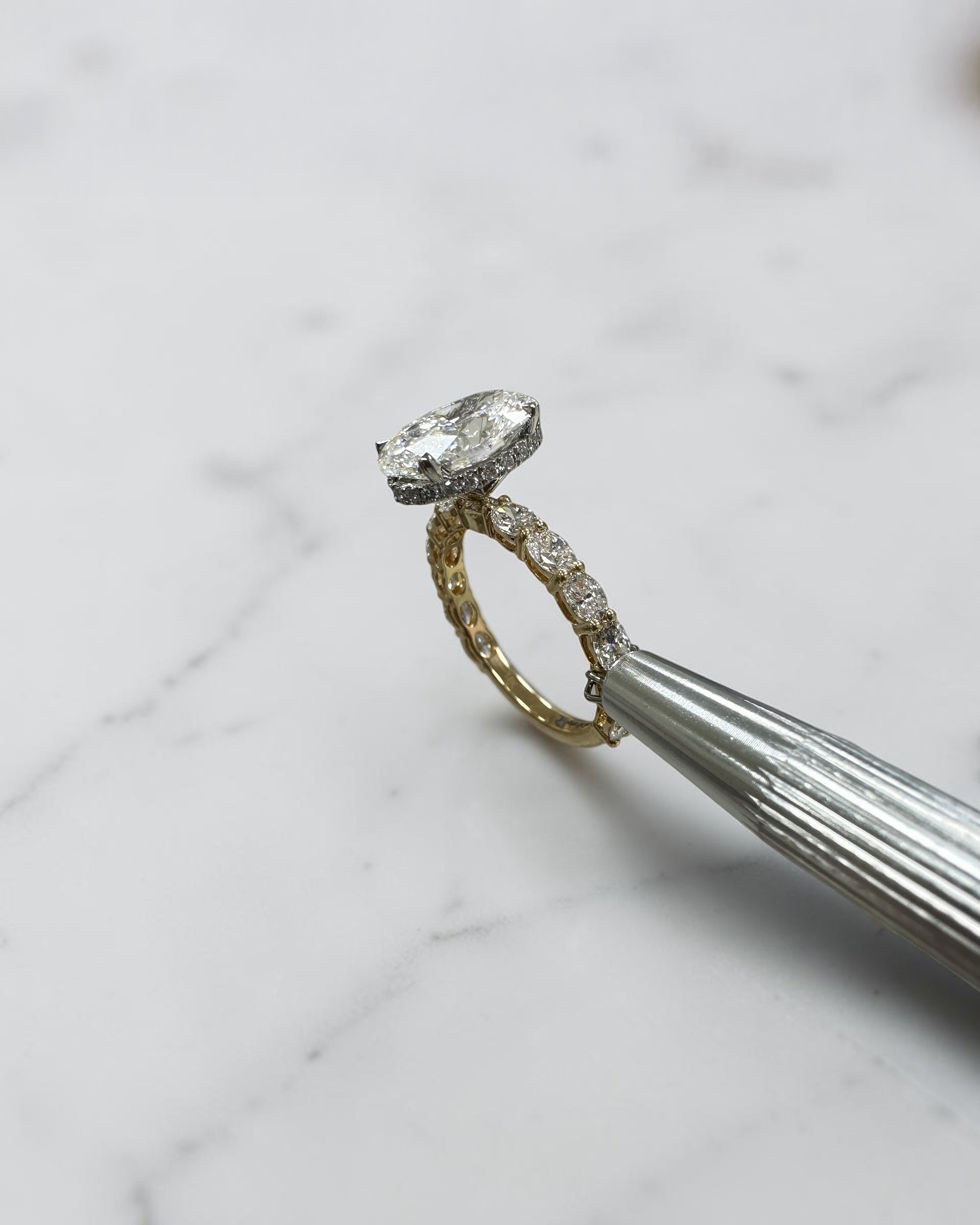 3ct oval cut lab grown diamond hidden halo engagement ring with east west oval diamond band in two tone platinum and 18kt yellow gold.