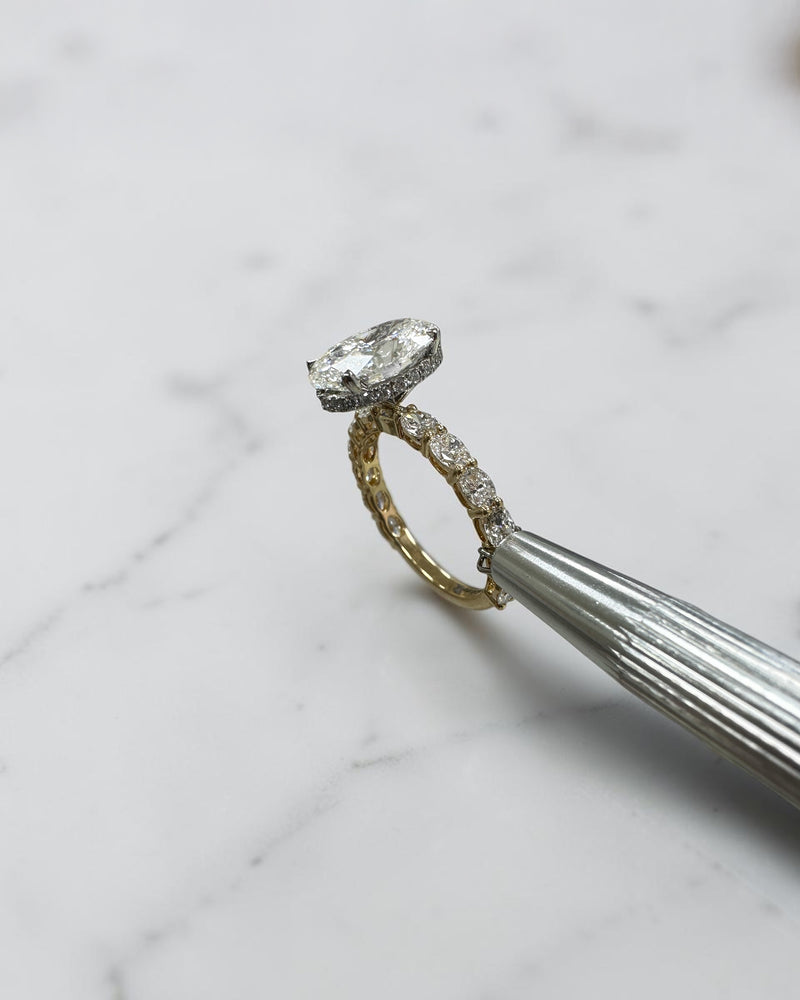 3ct oval cut lab grown diamond hidden halo engagement ring with east west oval diamond band in two tone platinum and 18kt yellow gold.