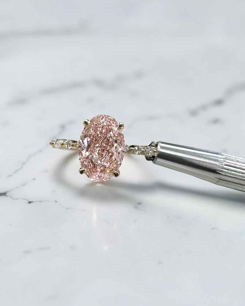 3ct pink oval cut lab grown diamond engagement ring with a floating setting, marquise and round diamond band in 18ct yellow gold, handcrafted in London by Layla Diamonds.