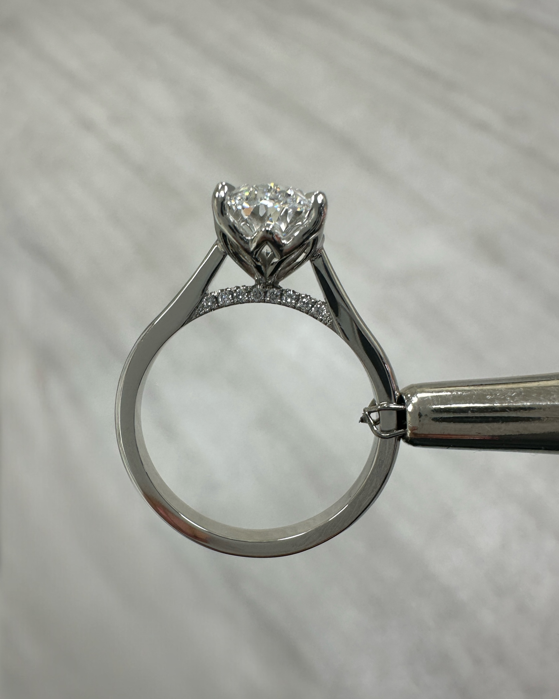 Close up of 3ct oval diamond solitaire ring in platinum cathedral setting with diamond bridge detail lotus head prongs — Layla Diamonds London.