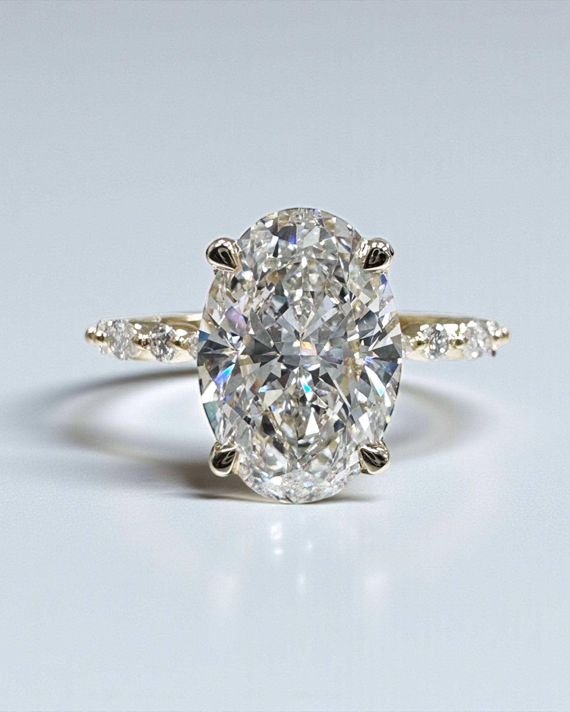 Oval 3ct lab grown diamond ring featuring marquise and round diamond band and delicate hidden halo 18kt yellow gold