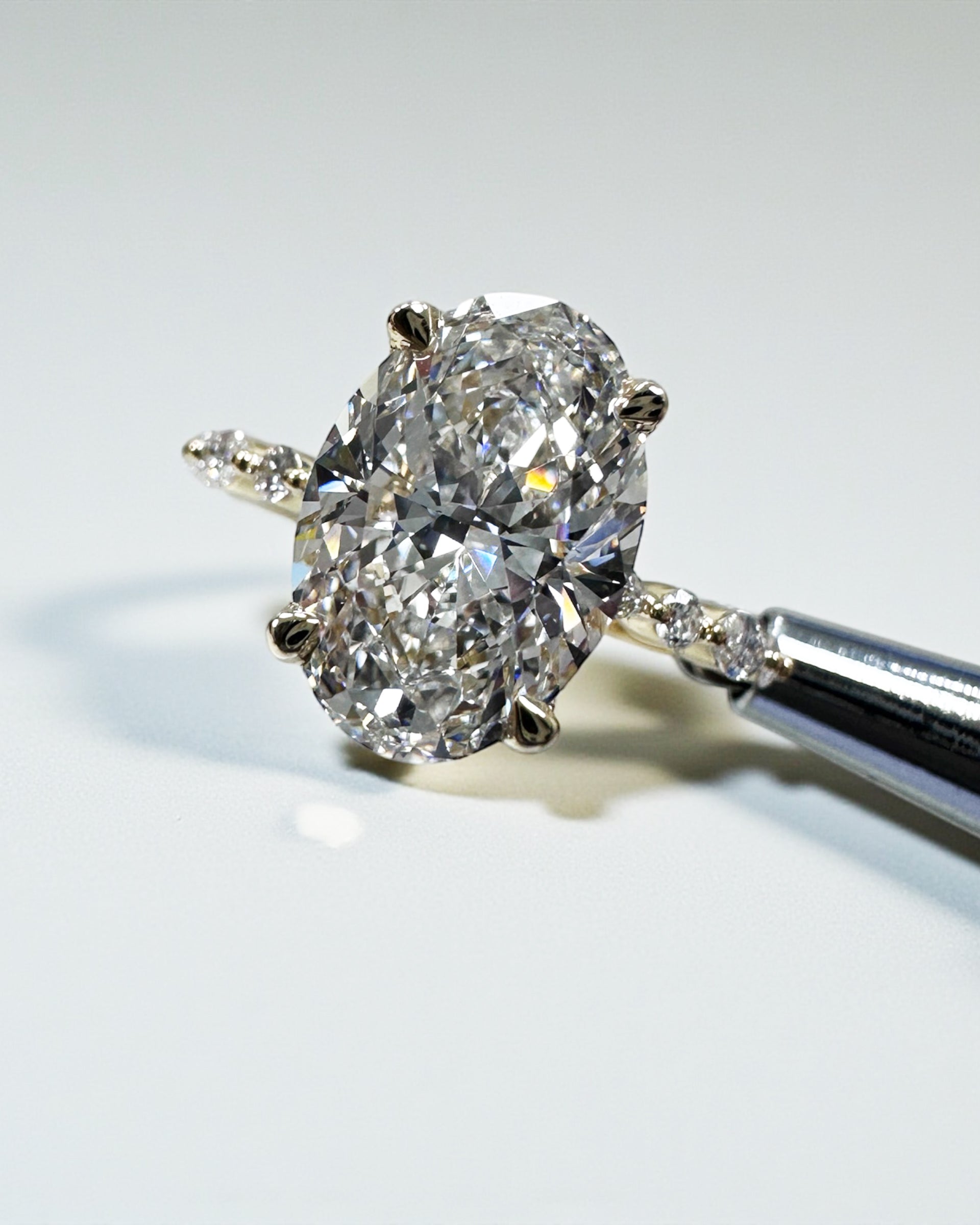 Oval 3ct lab grown diamond ring featuring marquise and round diamond band and delicate hidden halo 18kt yellow gold