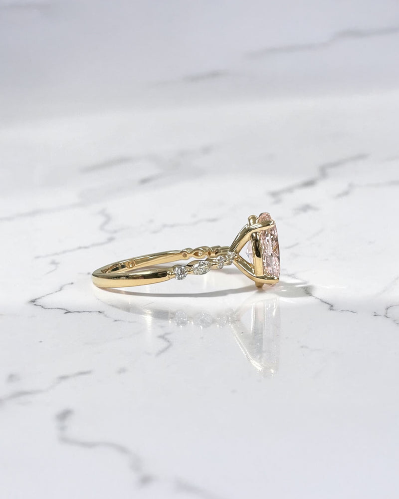 3ct pink oval cut lab grown diamond engagement ring with a floating setting, marquise and round diamond band in 18ct yellow gold, handcrafted in London by Layla Diamonds.