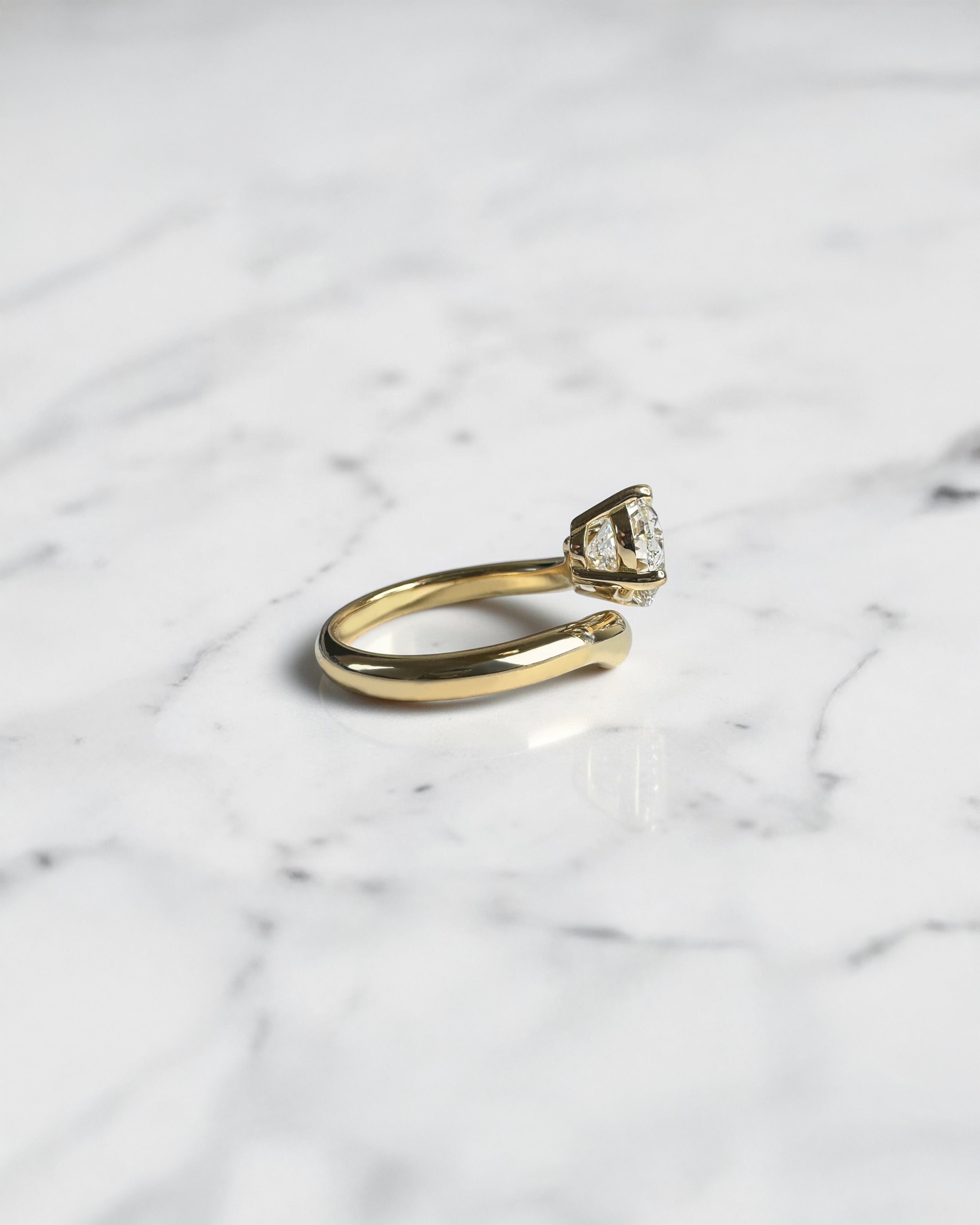 Side view of oval diamond wrap engagement ring with open band bypass setting in 18kt yellow gold