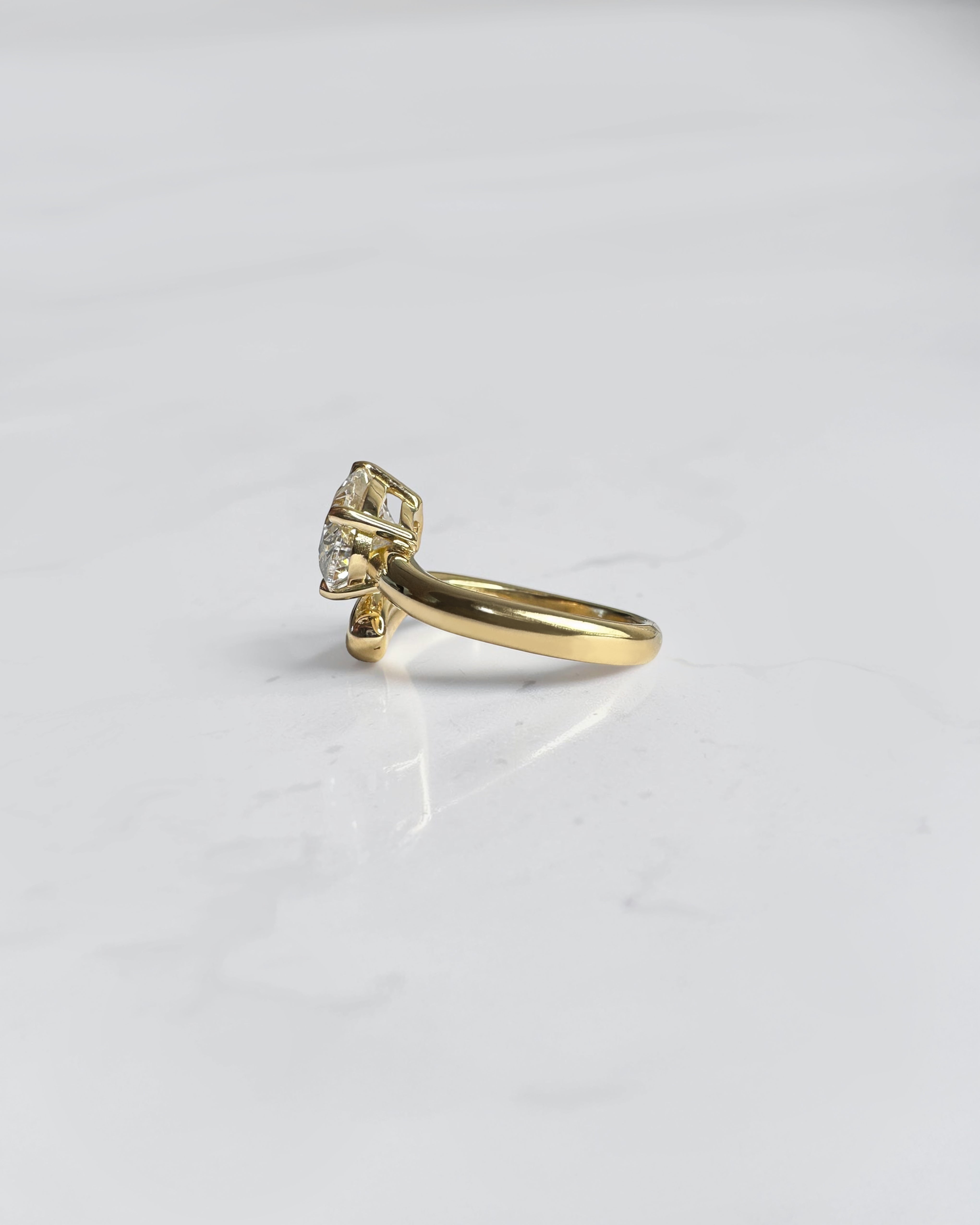 Side view of oval diamond wrap engagement ring with open band bypass setting in 18kt yellow gold