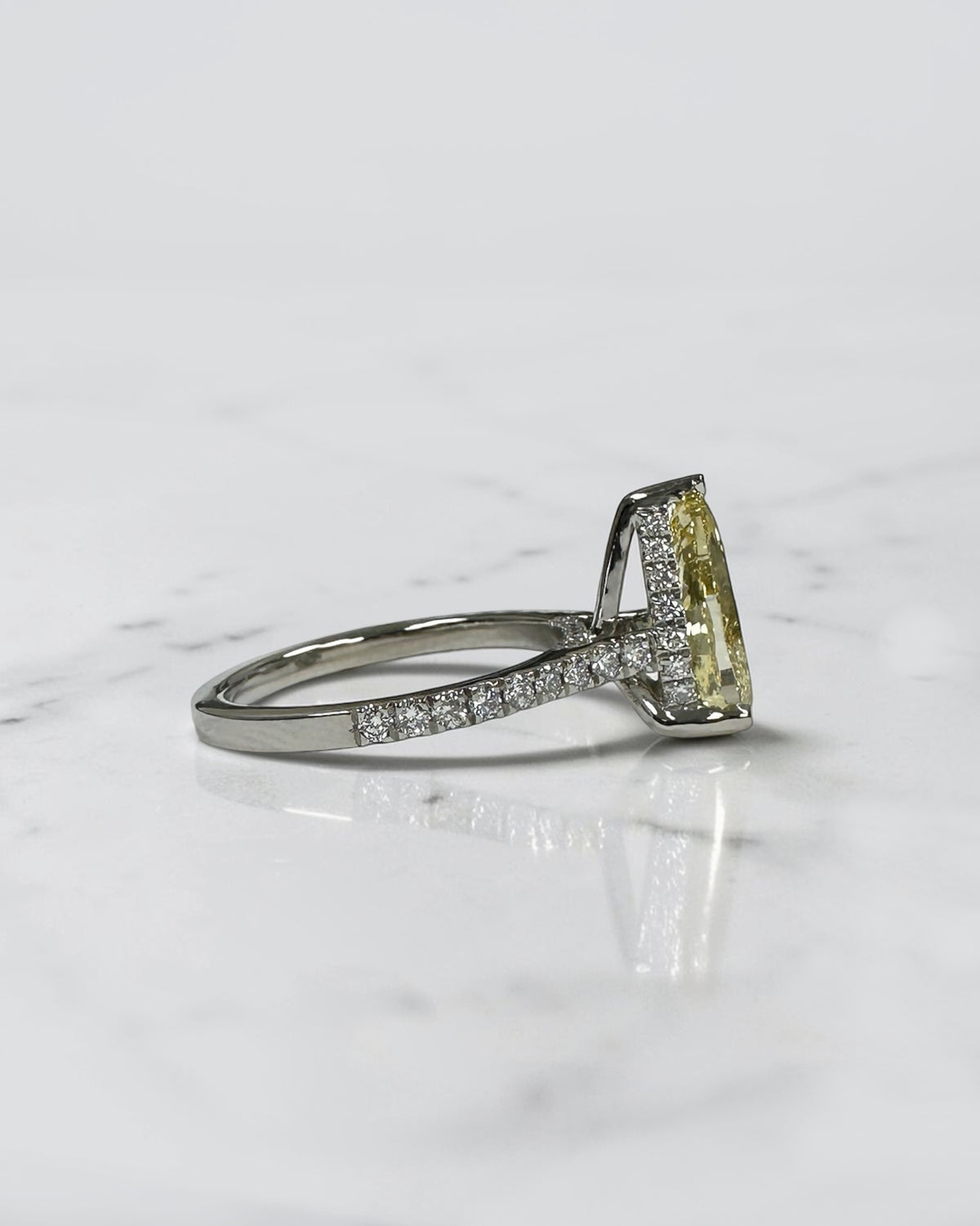 Side view of 3ct yellow pear diamond ring with cathedral setting and diamond hidden halo