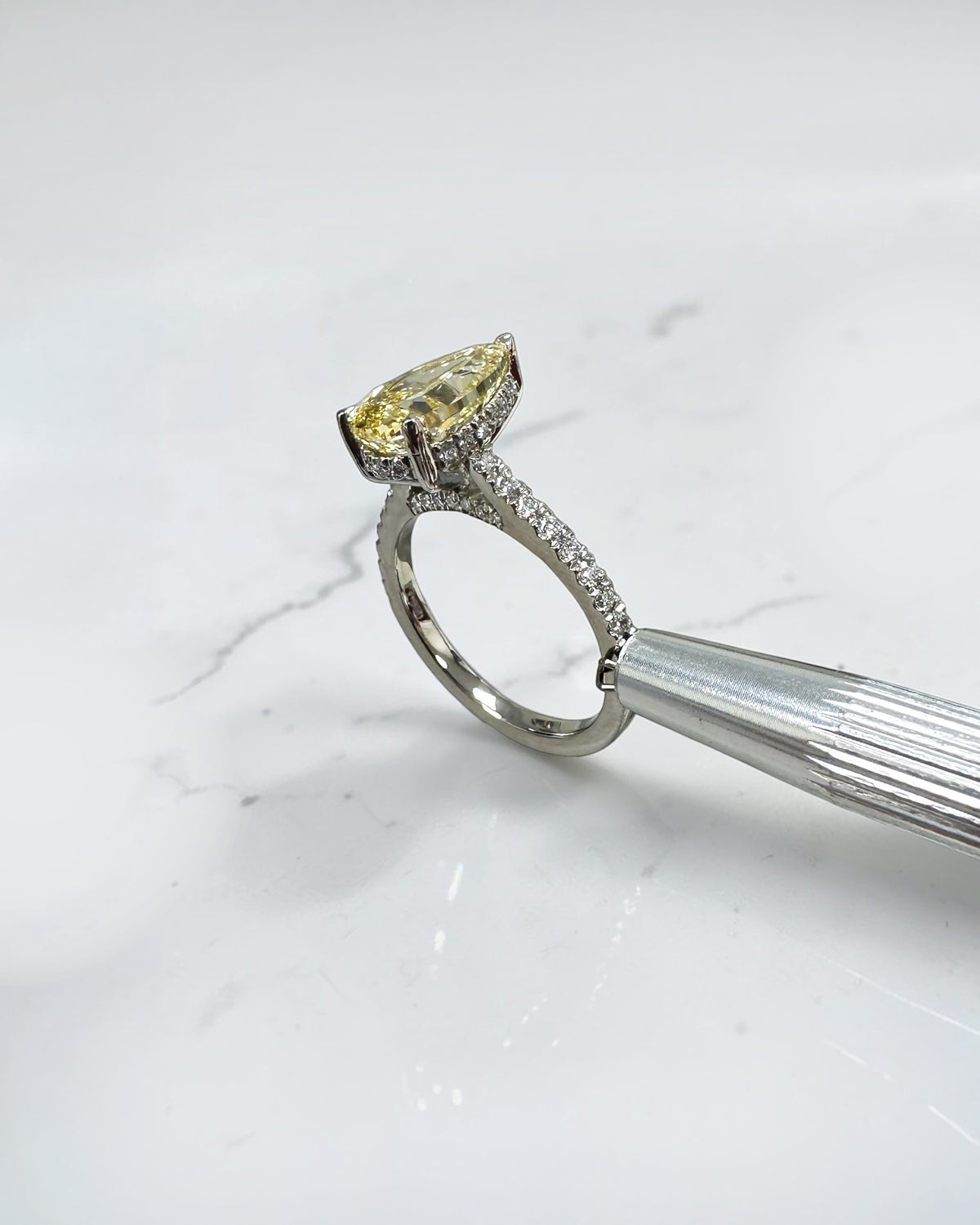 Yellow pear shaped diamond cathedral engagement ring with diamond set shoulders