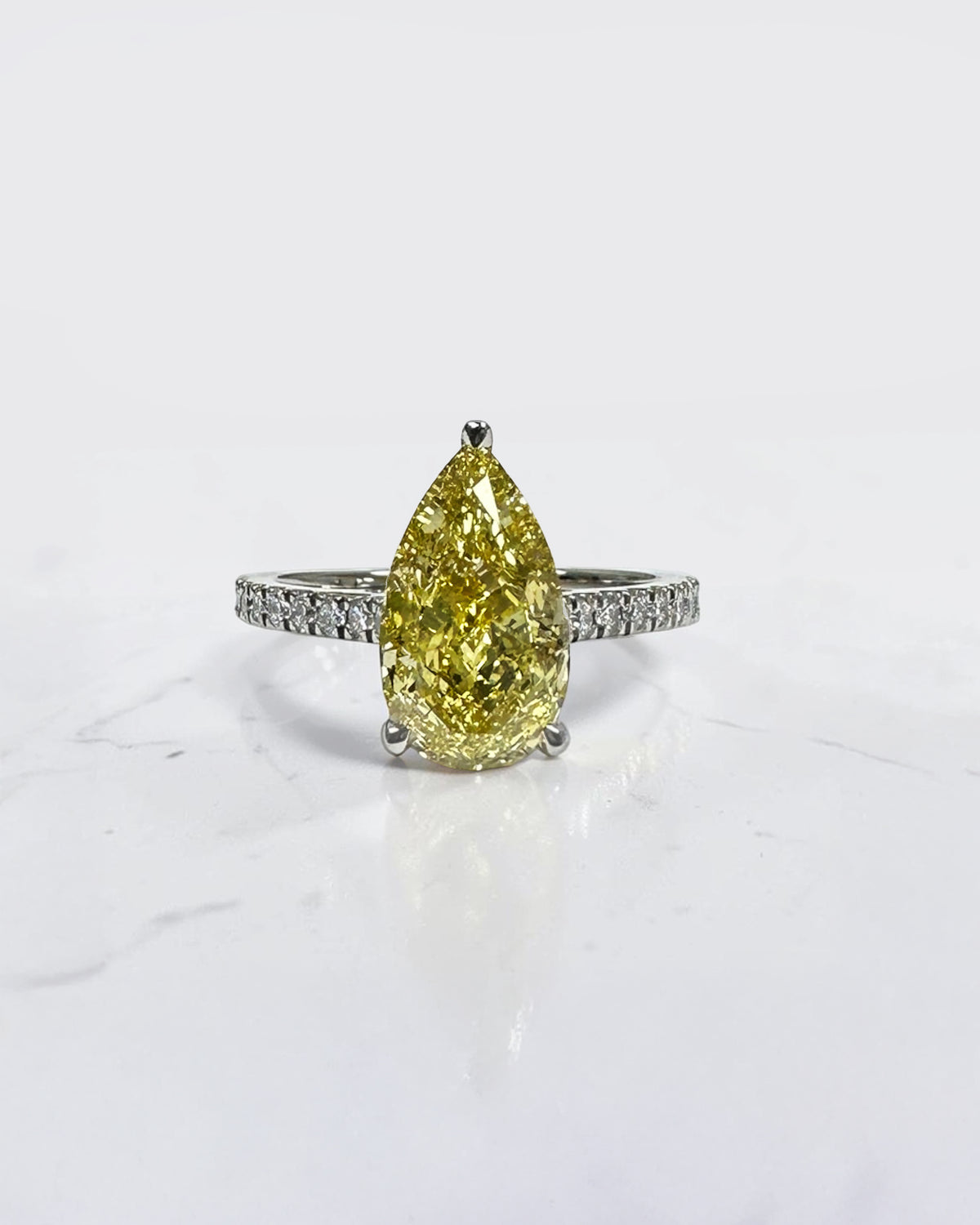 3ct yellow pear cut diamond engagement ring with white diamond band and three claw setting