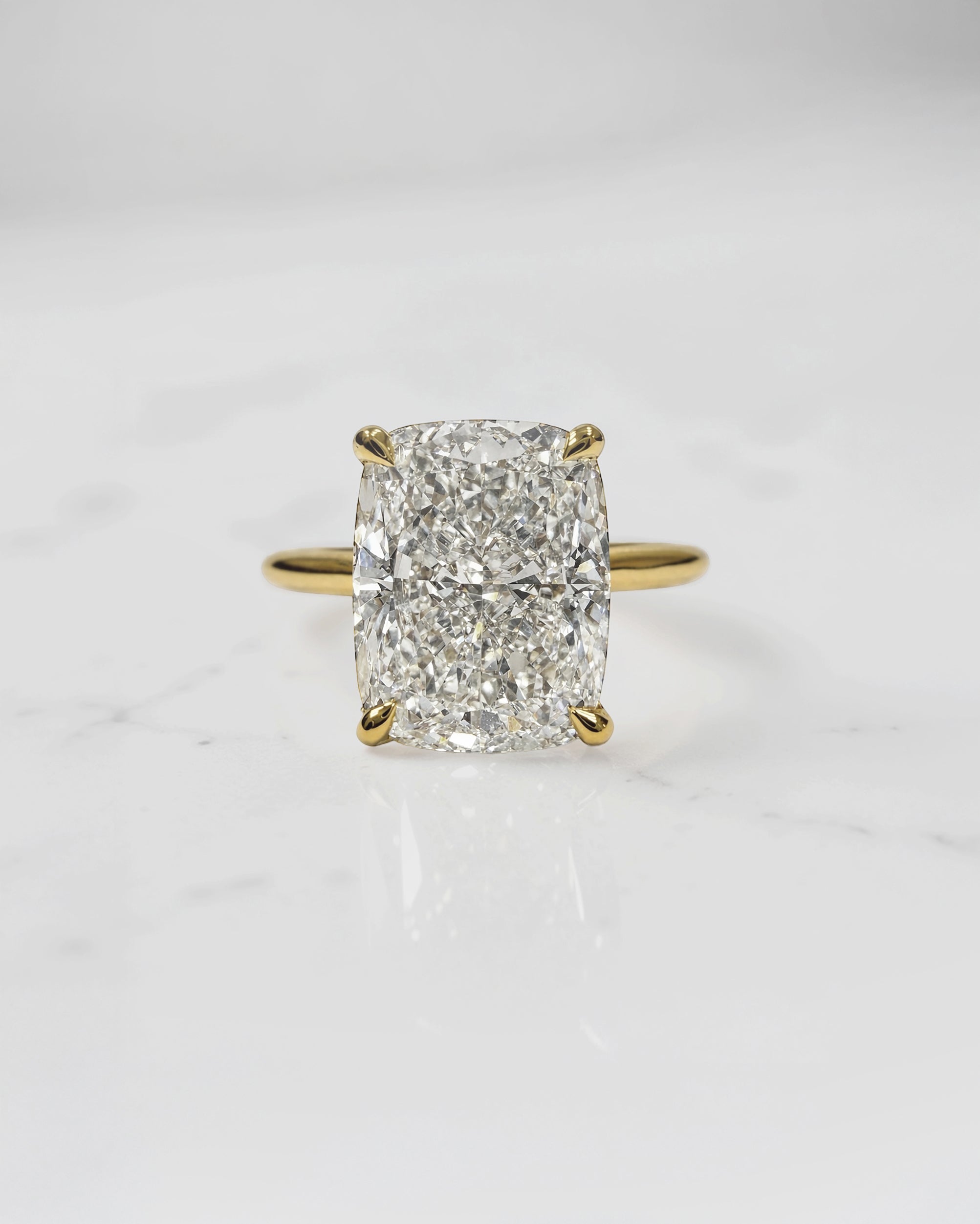 4ct elongated cushion cut lab grown diamond engagement ring in 18kt yellow gold with cathedral setting and hidden halo.