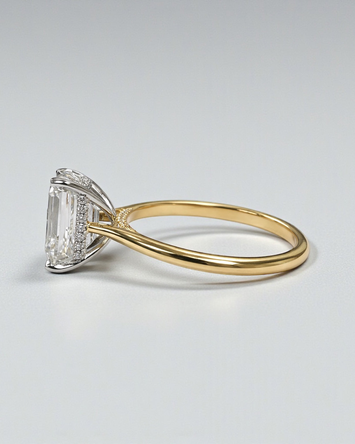 4ct emerald cut lab grown diamond engagement ring with hidden halo and diamond bridge in a cathedral setting 18kt yellow gold 