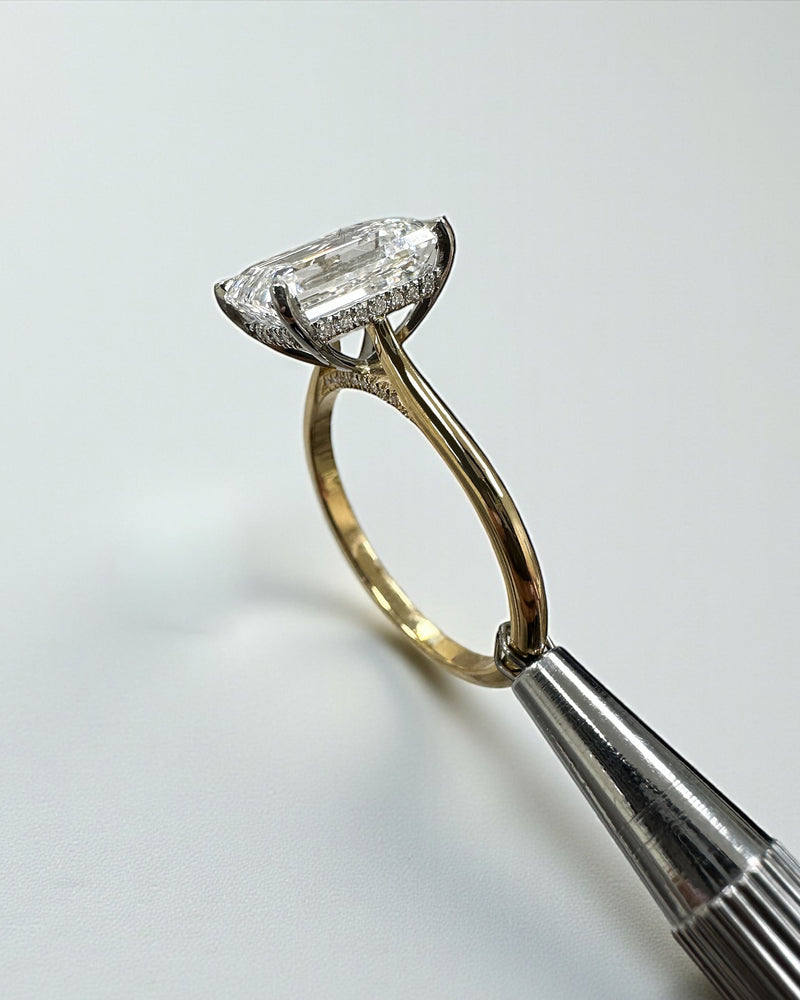 4ct emerald cut lab grown diamond engagement ring with hidden halo and diamond bridge in a cathedral setting 18kt yellow gold 