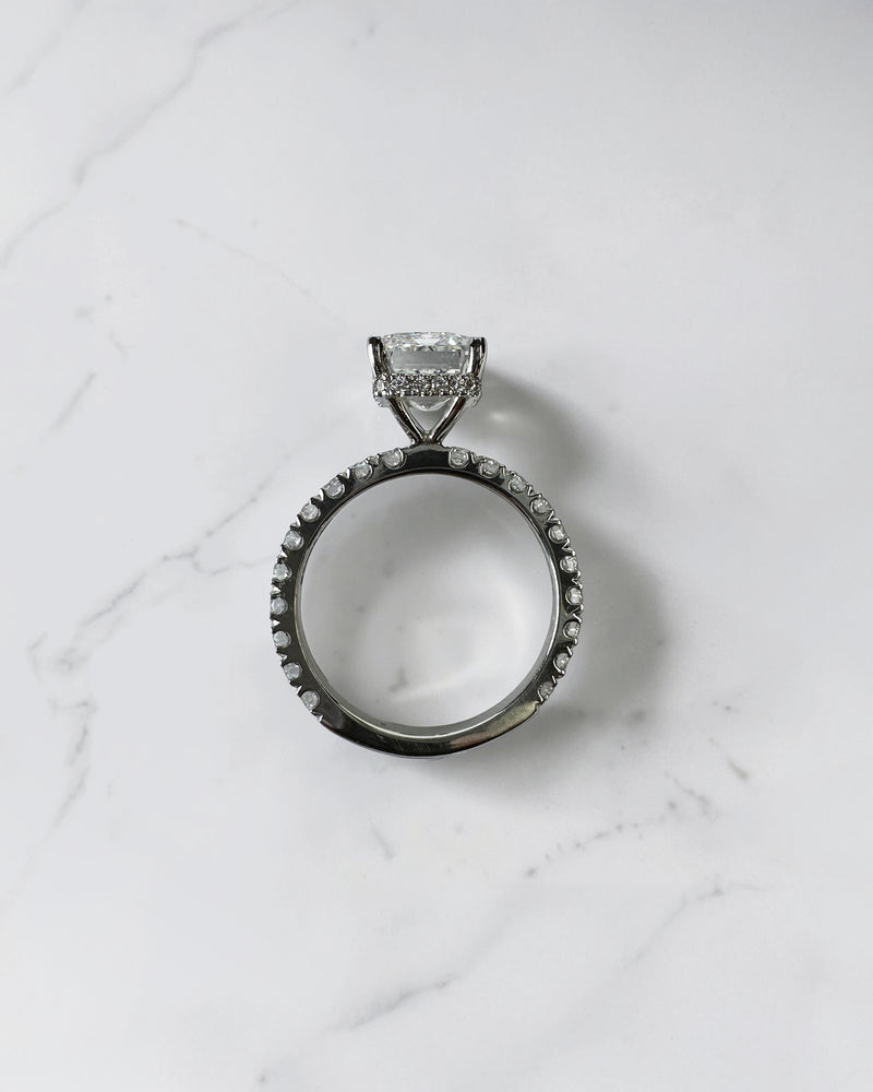 4ct emerald cut lab grown diamond engagement ring with floating diamond shoulder band and diamond wrap around hidden halo in platinum.