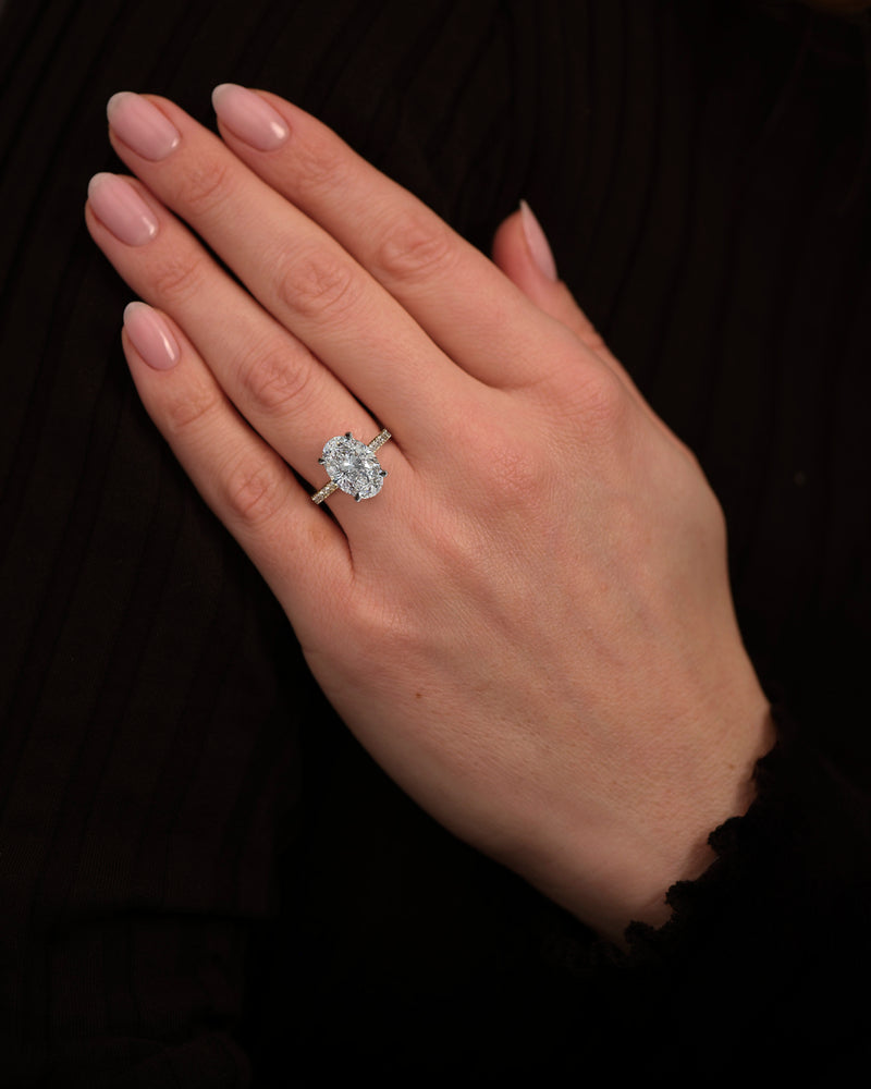 4ct oval cut lab grown diamond engagement ring on hand with lotus head setting and diamond shoulders in yellow gold with platinum head made in London, Layla Diamonds
