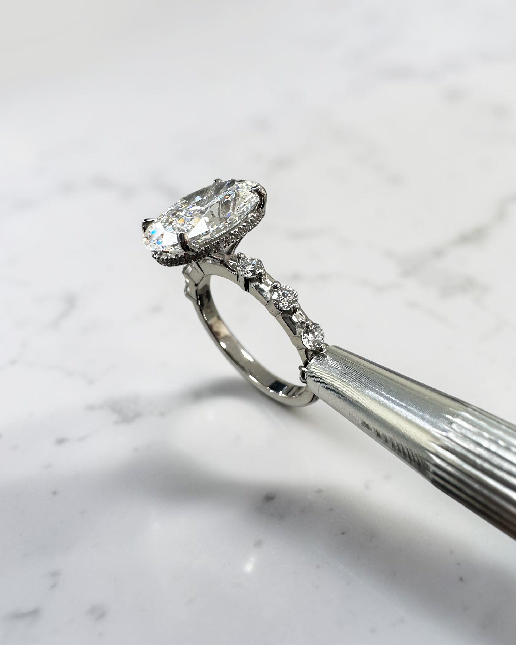 4ct oval lab grown diamond hidden halo engagement ring with floating cathedral setting and spaced diamond band in platinum.