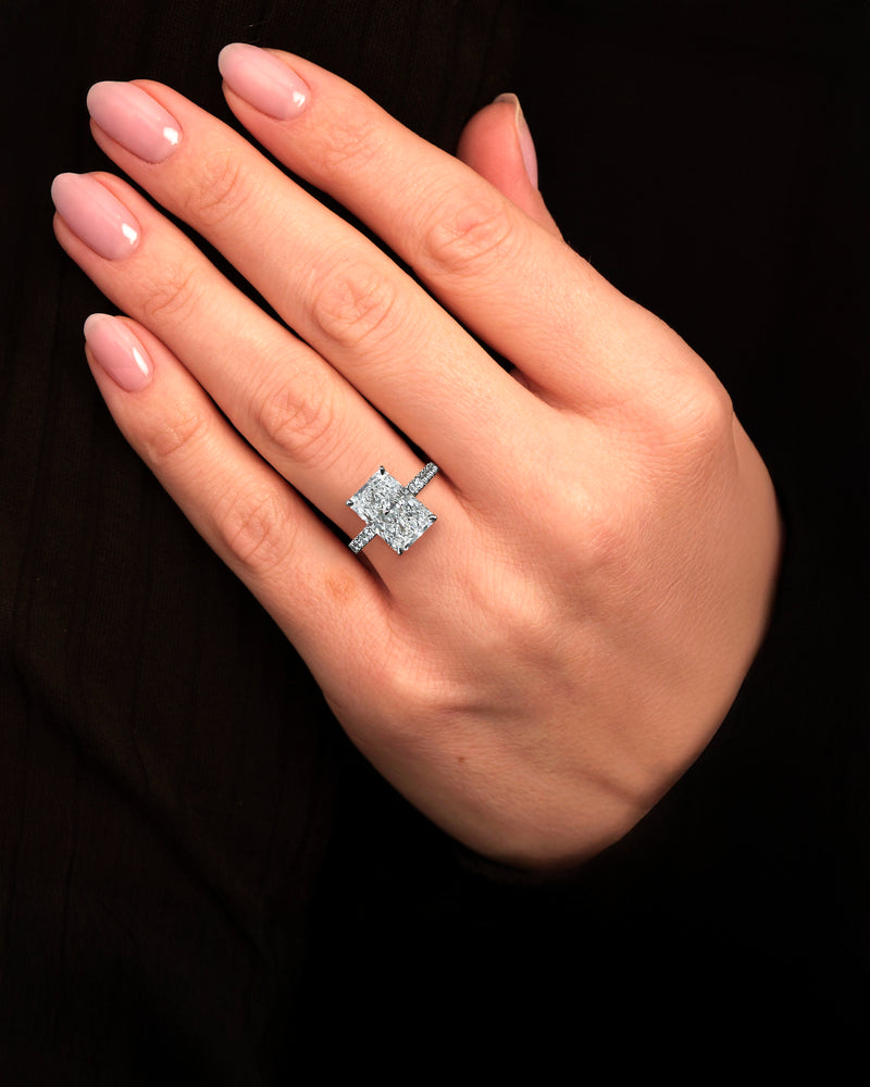 4ct radiant cut lab grown diamond engagement ring on hand with cathedral setting, hidden halo and diamond band. Available in platinum or 18kt yellow or white gold, London