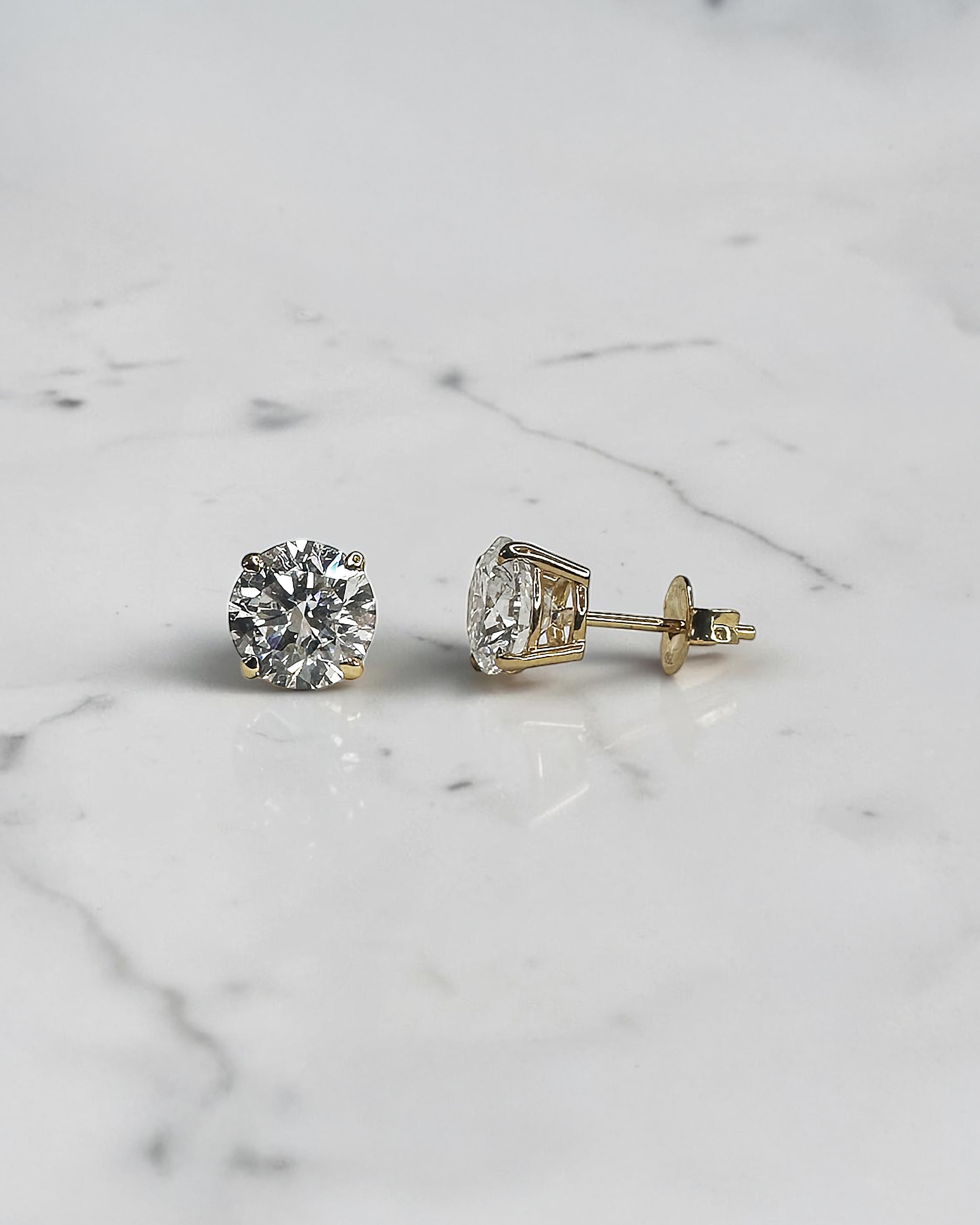 4ct round brilliant lab grown diamond stud earrings featuring 2ct E/F VS1+ lab grown diamonds with Ideal Cut, Excellent Polish, Excellent Symmetry and No Fluorescence in a four prong basket setting.