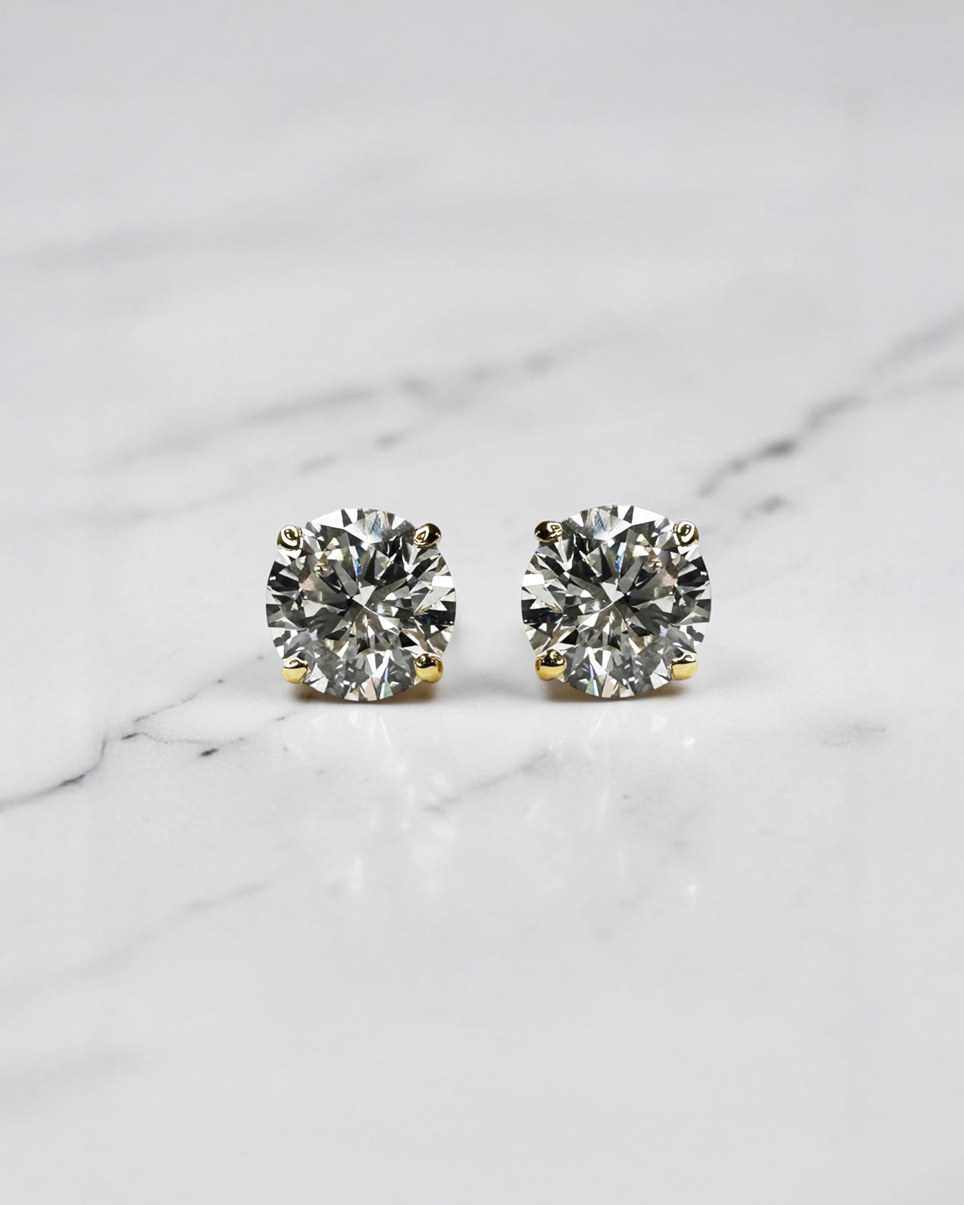 4ct round brilliant lab grown diamond stud earrings featuring 2ct E/F VS1+ lab grown diamonds with Ideal Cut, Excellent Polish, Excellent Symmetry and No Fluorescence in a four prong basket setting.