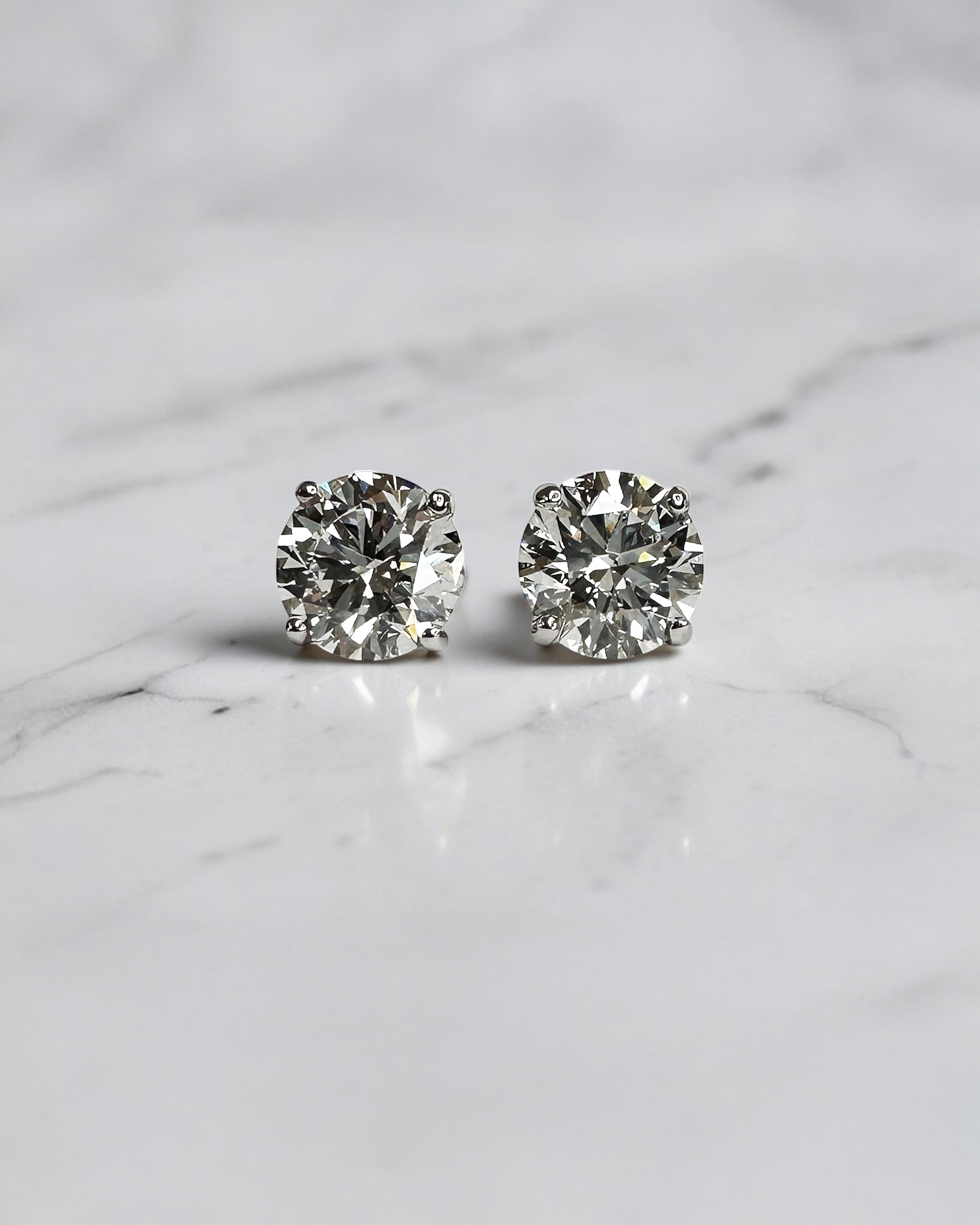 4ct round brilliant lab grown diamond stud earrings featuring 2ct E/F VS1+ lab grown diamonds with Ideal Cut, Excellent Polish, Excellent Symmetry and No Fluorescence in a four prong basket setting.