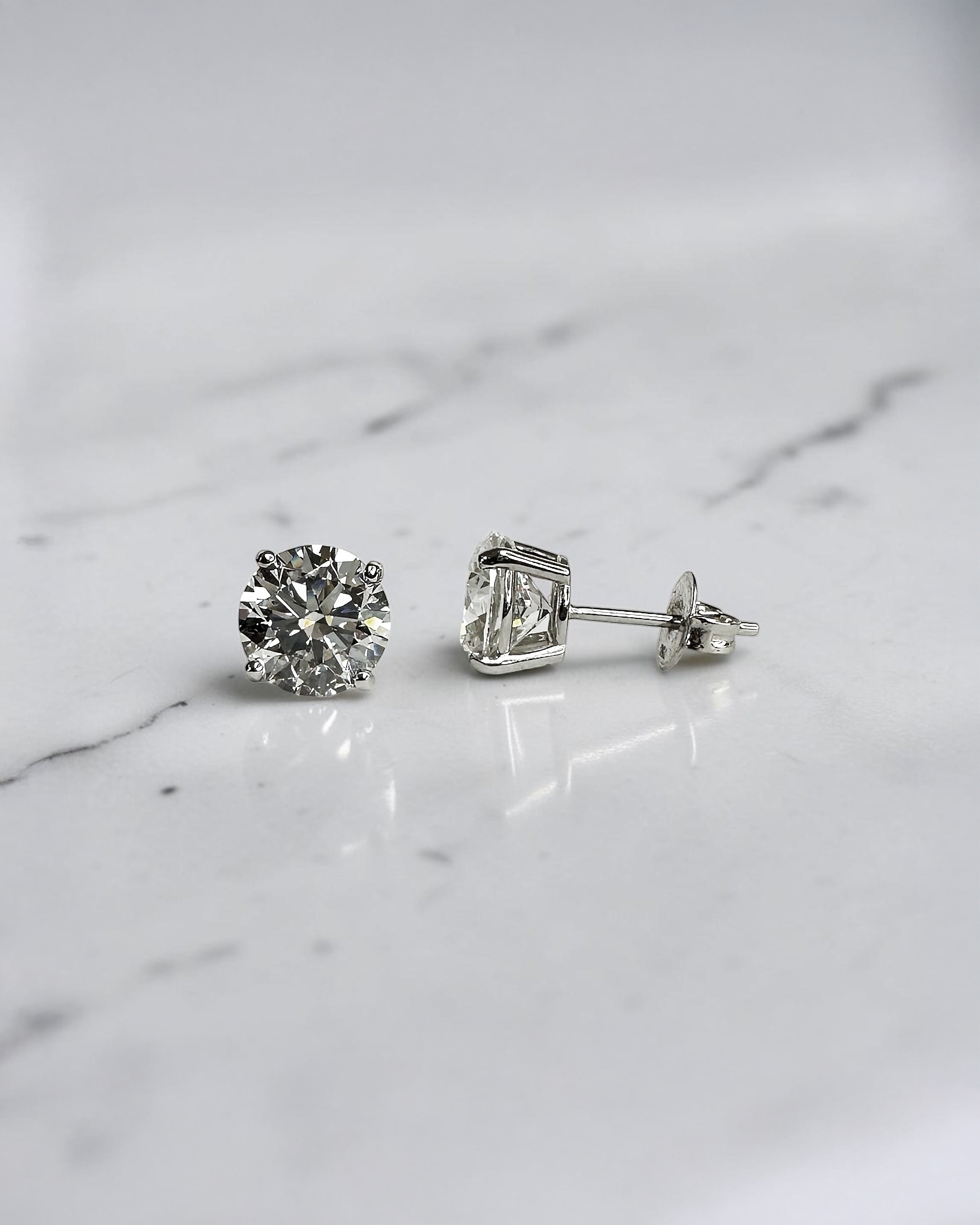4ct round brilliant lab grown diamond stud earrings featuring 2ct E/F VS1+ lab grown diamonds with Ideal Cut, Excellent Polish, Excellent Symmetry and No Fluorescence in a four prong basket setting.