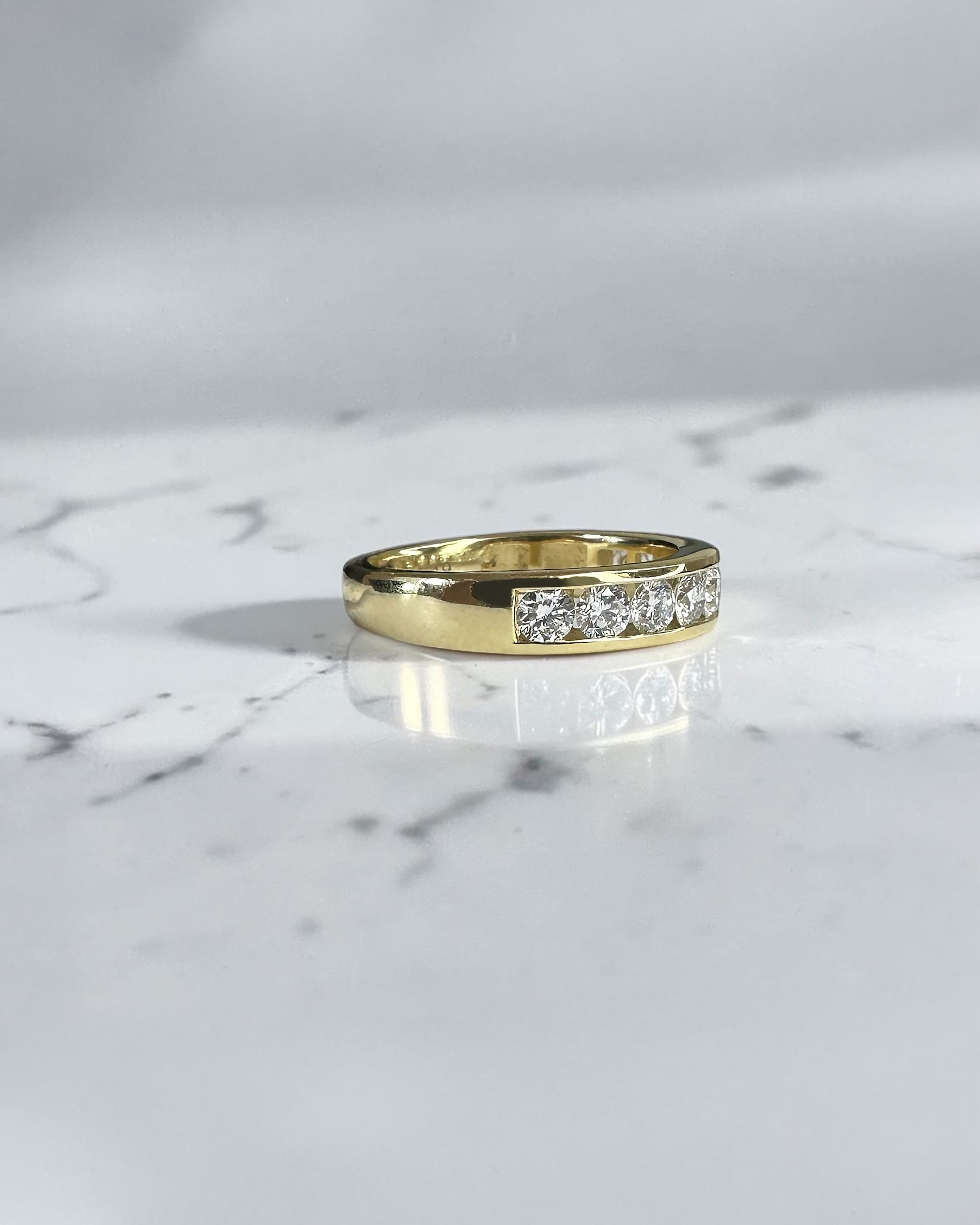 4mm channel set round diamond wedding band in yellow gold featuring 0.80ct of round brilliant diamonds set halfway around the band.