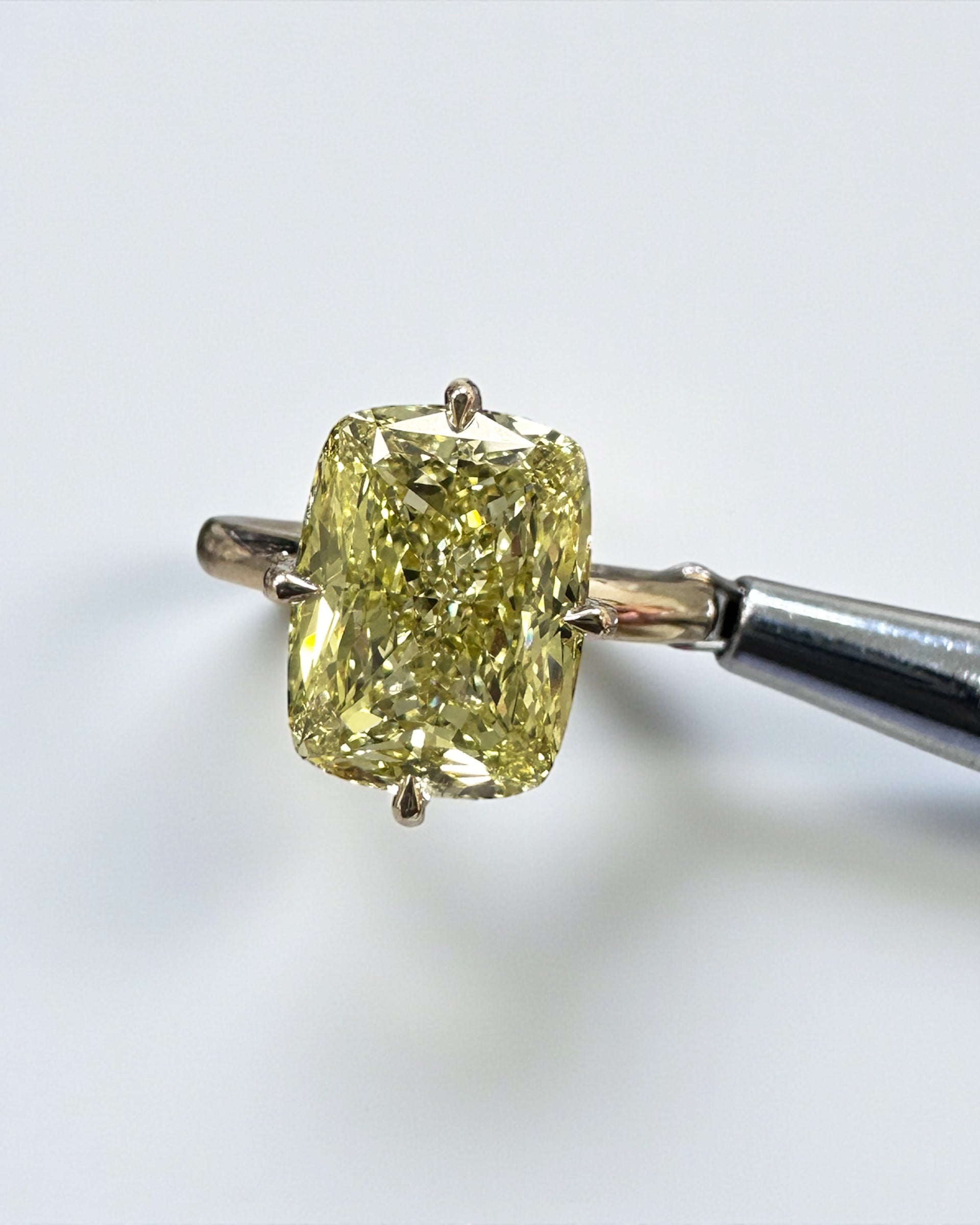 A stunning 5ct Fancy Intense Yellow elongated cushion cut diamond solitaire with platinum hidden halo and 18kt yellow gold band engagement ring. Bold, elegant and handcrafted in London.