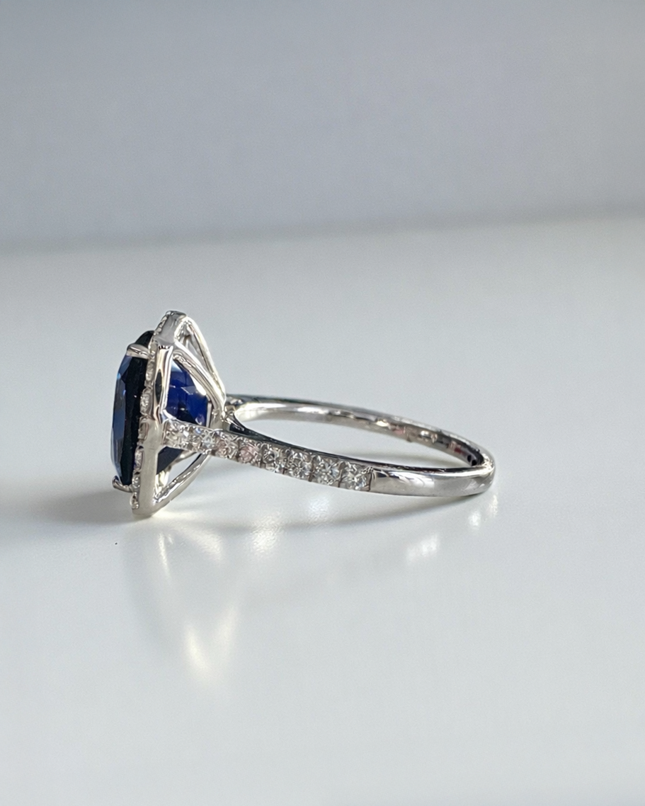 Striking 5ct lab grown blue sapphire halo diamond ring with diamond shoulders. Available in 9kt or 18kt gold or platinum. Made to order. Layla Diamonds London