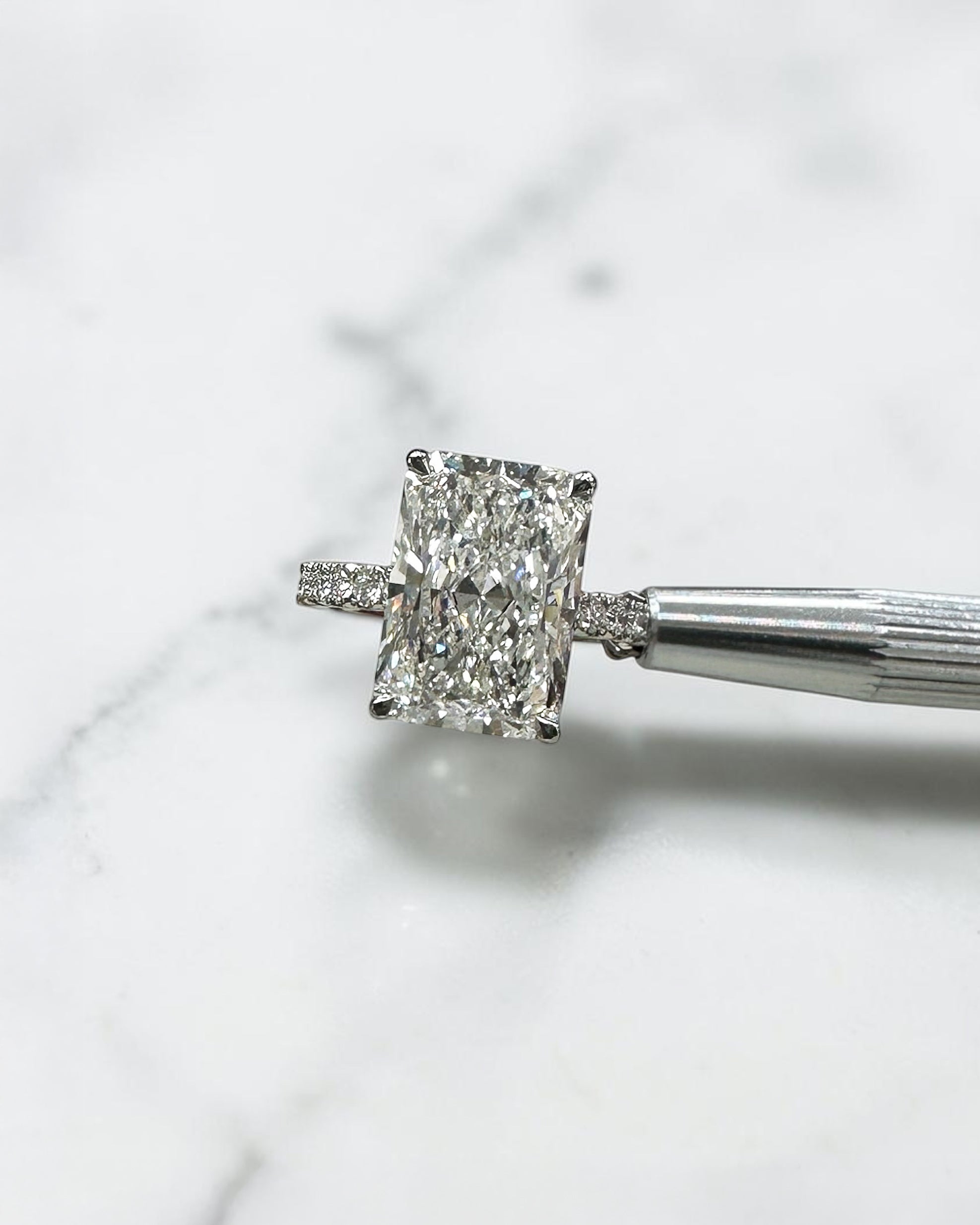 7ct radiant cut lab grown diamond engagement ring with diamond shoulder band, floating setting and wrap around hidden halo, handmade in London.
