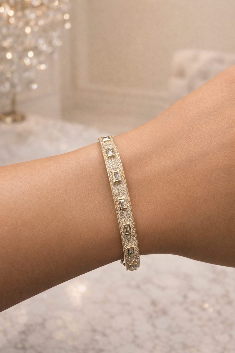 Diamond bangle in yellow gold with baguette and round brilliant cut diamonds on wrist, hand 