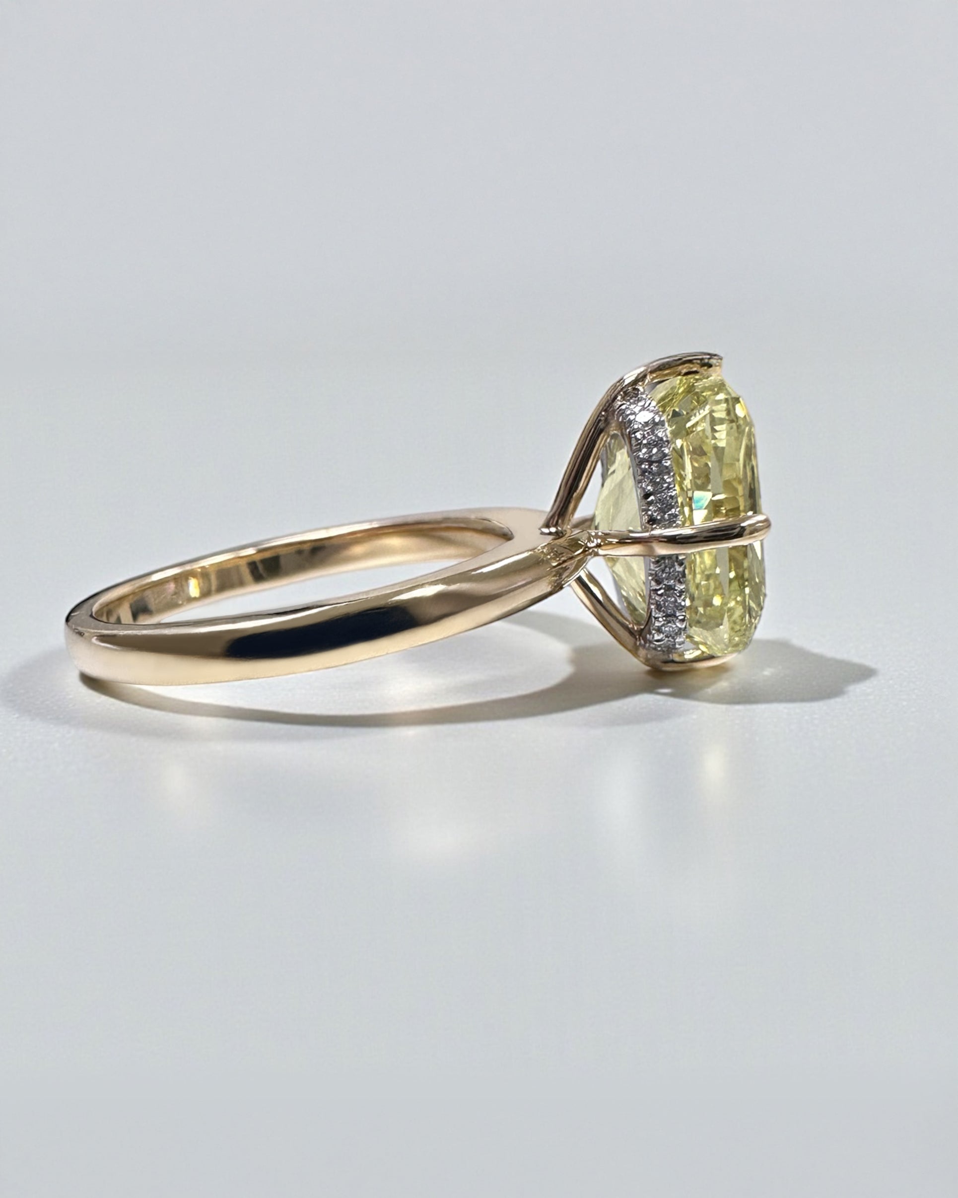 A stunning 5ct Fancy Intense Yellow elongated cushion cut diamond solitaire with platinum hidden halo and 18kt yellow gold band engagement ring. Bold, elegant and handcrafted in London.