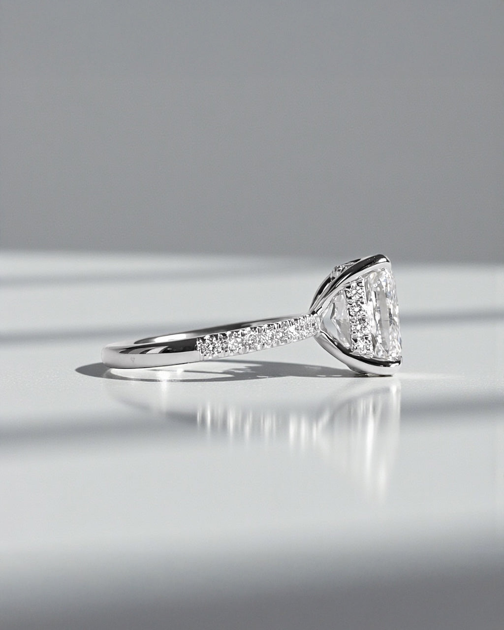 4ct cushion cut lab grown diamond engagement ring with diamond shoulders and hidden halo. Available in 18ct white, yellow, rose gold or platinum.