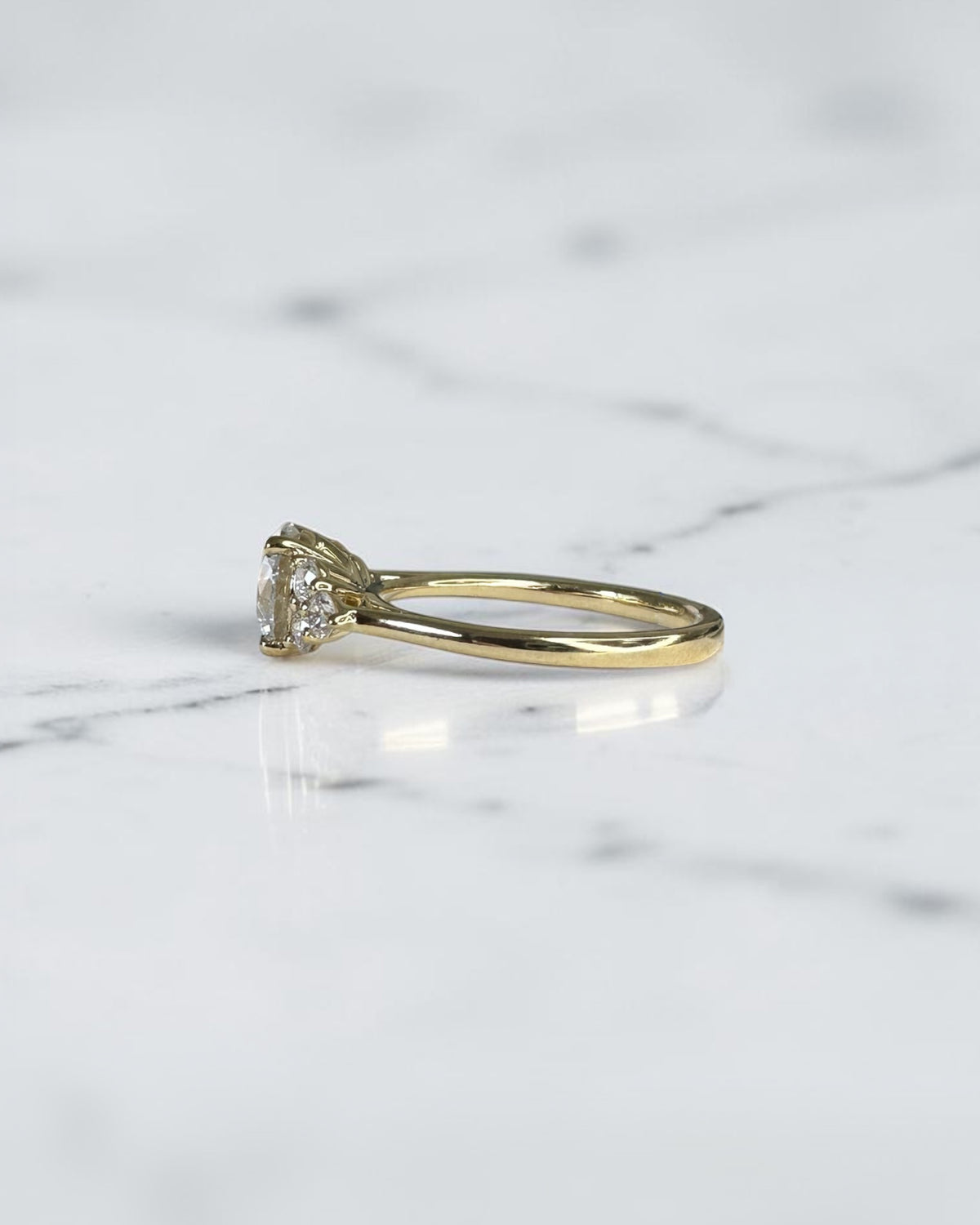 1.50ct round brilliant lab grown diamond trefoil engagement ring with diamond cluster shoulders in yellow gold.