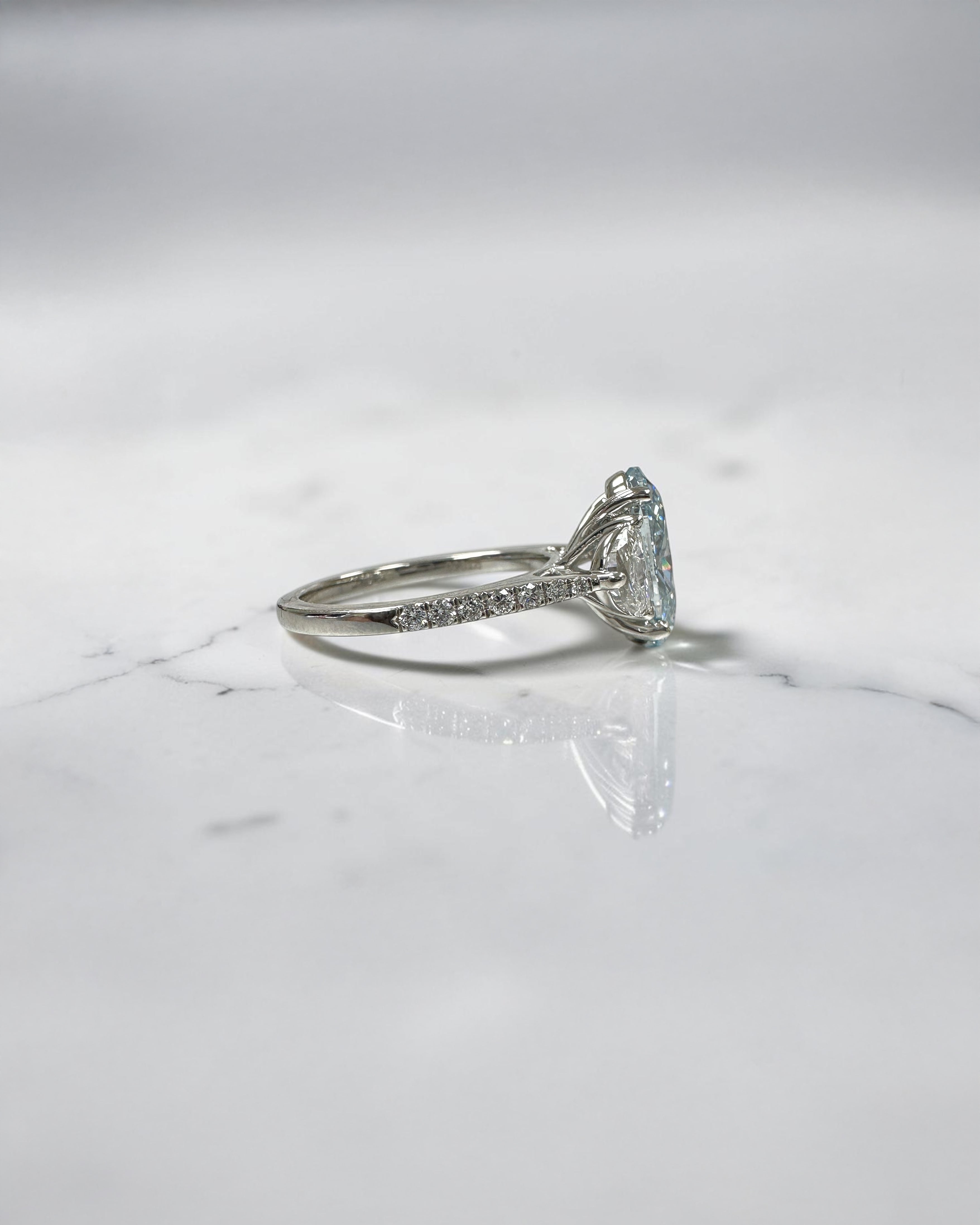 3.70ct baby fancy blue oval cut lab grown diamond trilogy engagement ring with half moon side stones and diamond set tapered shoulders in platinum setting 