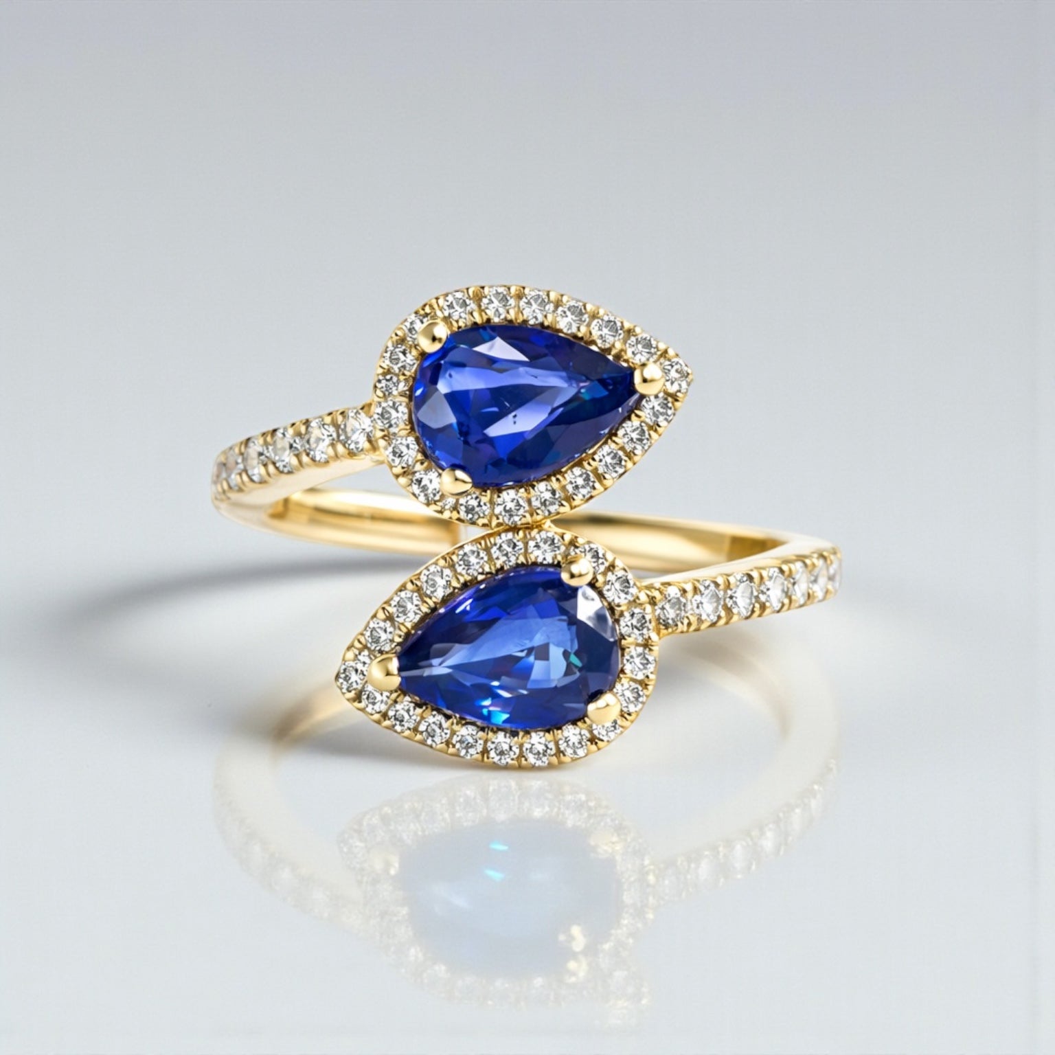 Two stone pear cut blue sapphire and diamond halo ring in 18kt yellow gold