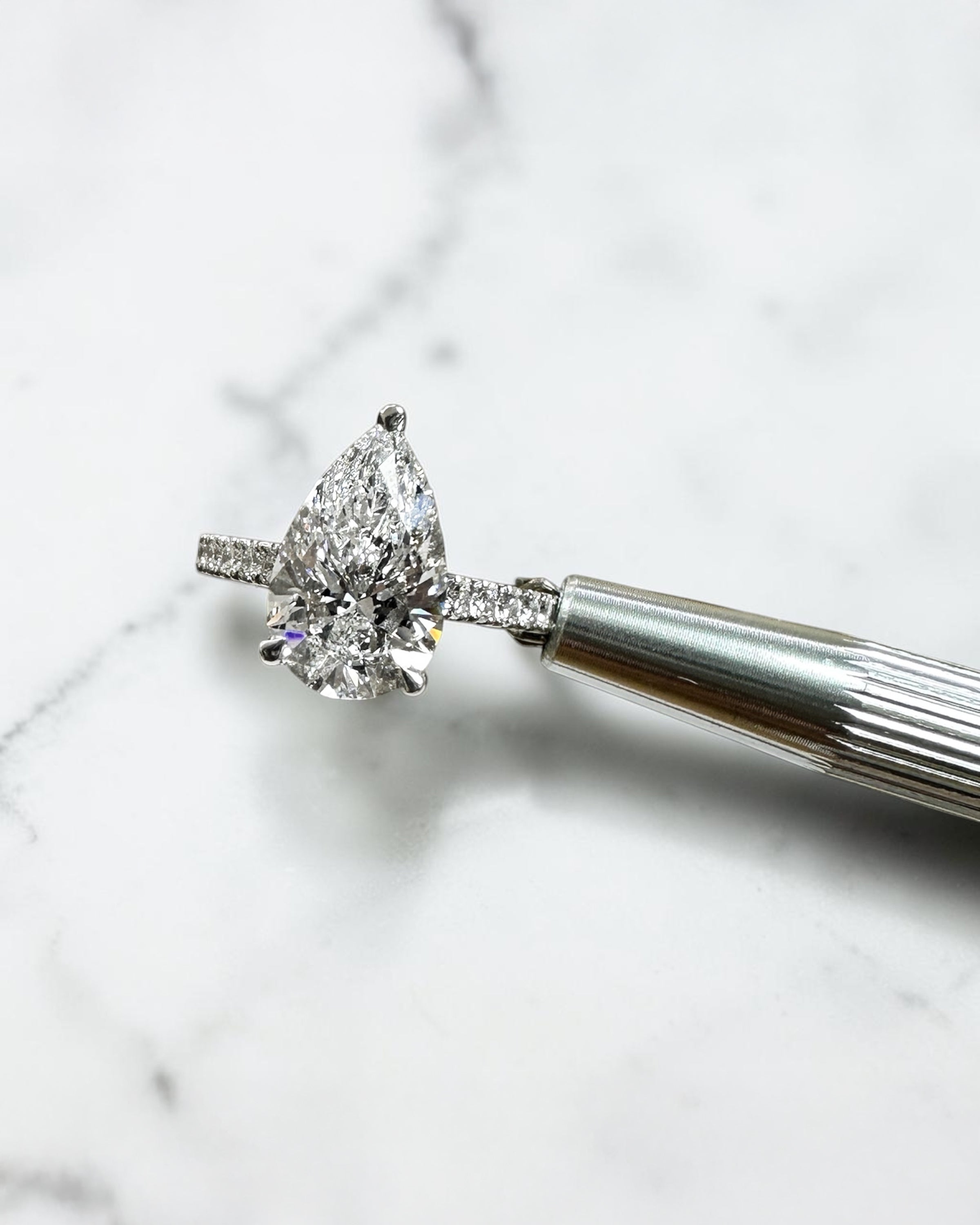 2ct pear cut lab grown diamond engagement ring with cathedral setting, diamond shoulder band, hidden halo and diamond bridge, handcrafted in platinum by Layla Diamonds.