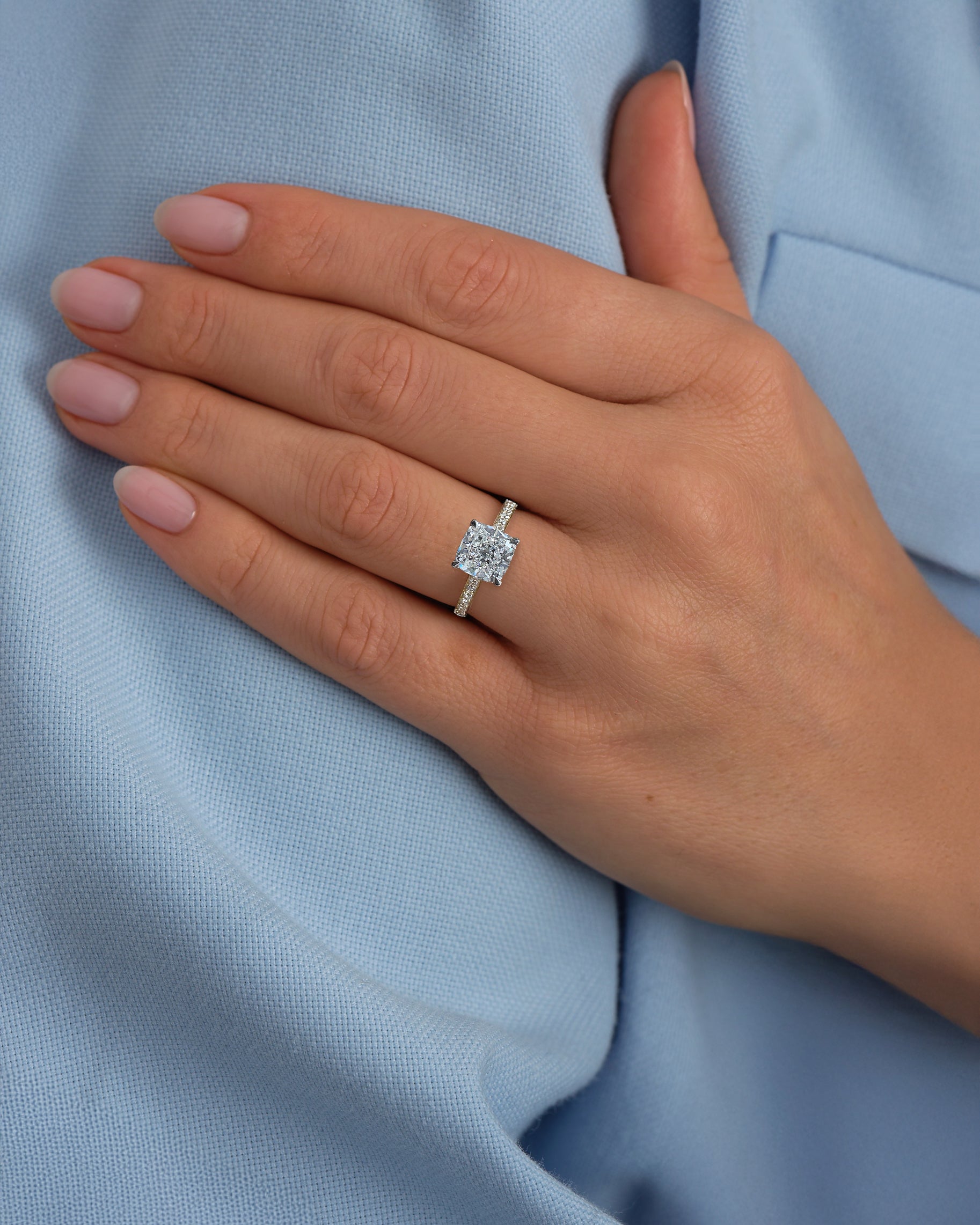 Two tone cushion cut diamond engagement ring worn on hand, featuring platinum head and channel set band 18kt yellow gold by Layla Diamonds